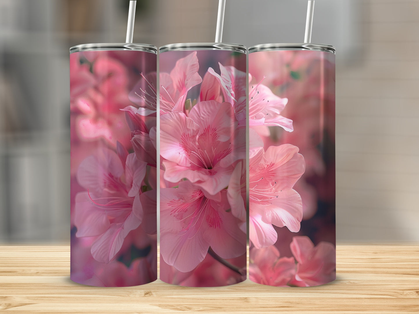 Three pink floral tumblers with straws on a wooden surface.