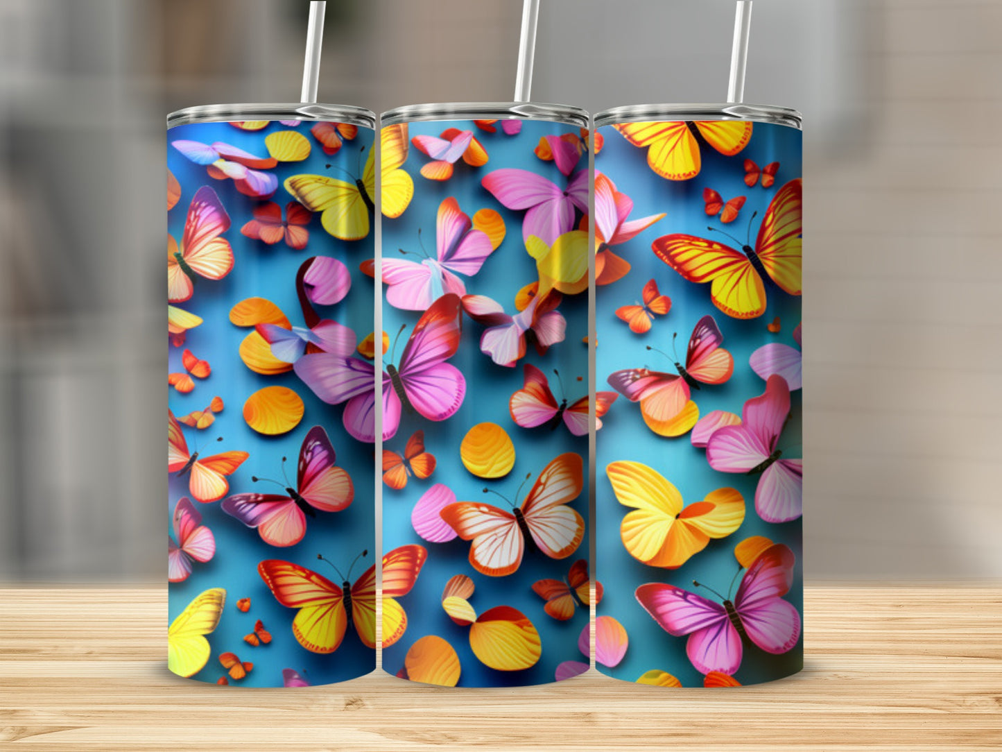 Three tumblers with colorful butterfly designs on a wooden surface.