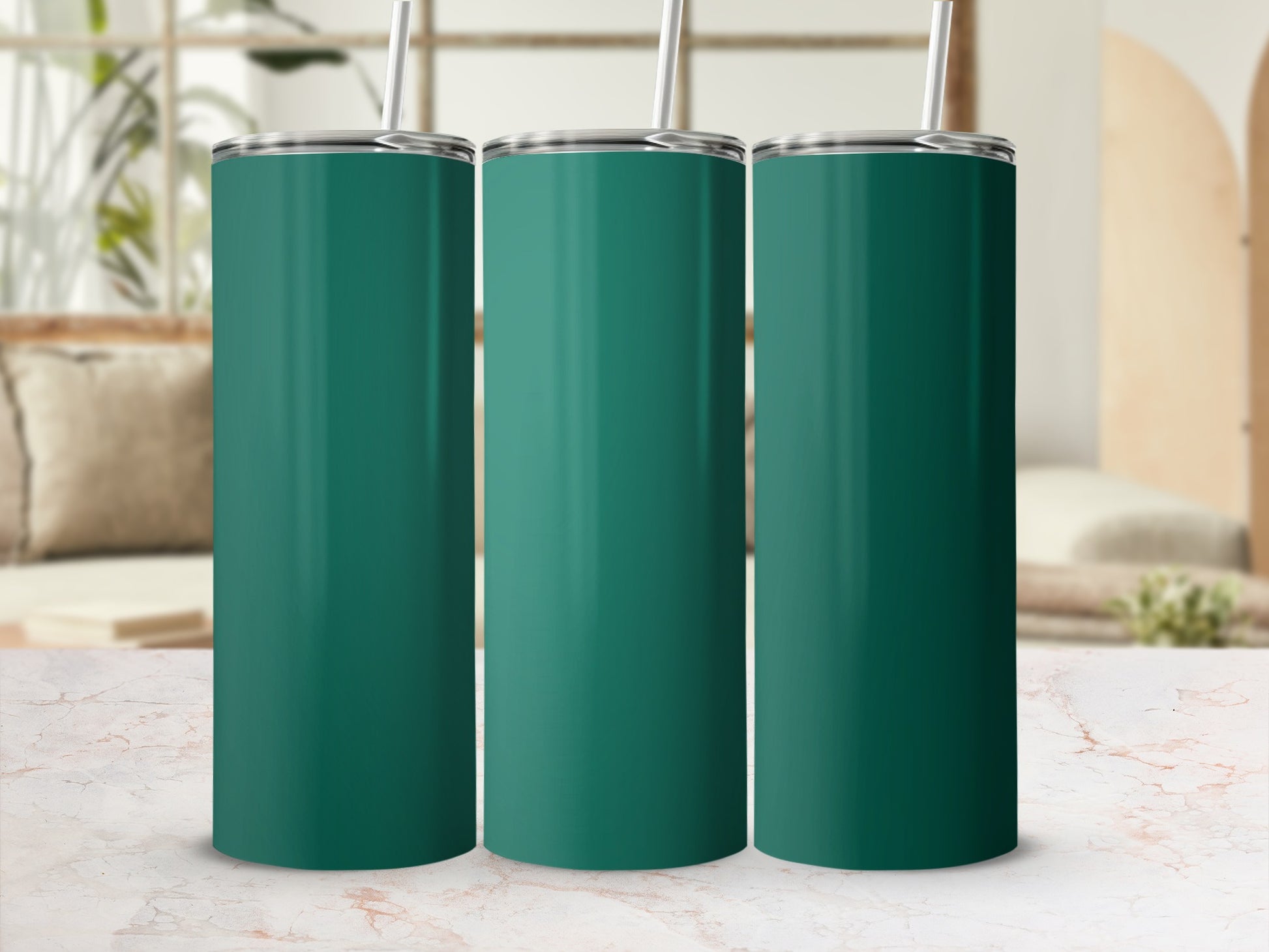 Three teal tumblers with straws arranged on a marble surface.