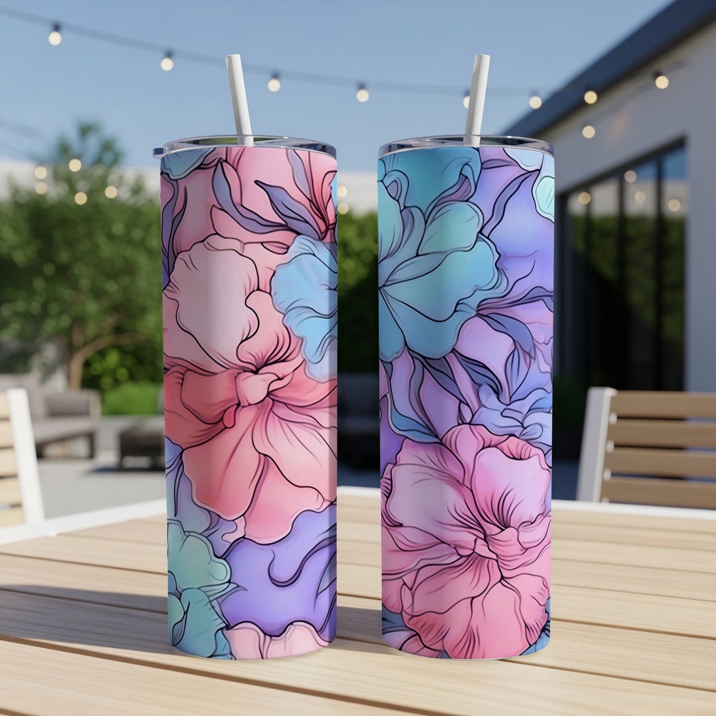 Two tumblers with a pastel floral design sit on a wooden table outdoors.
