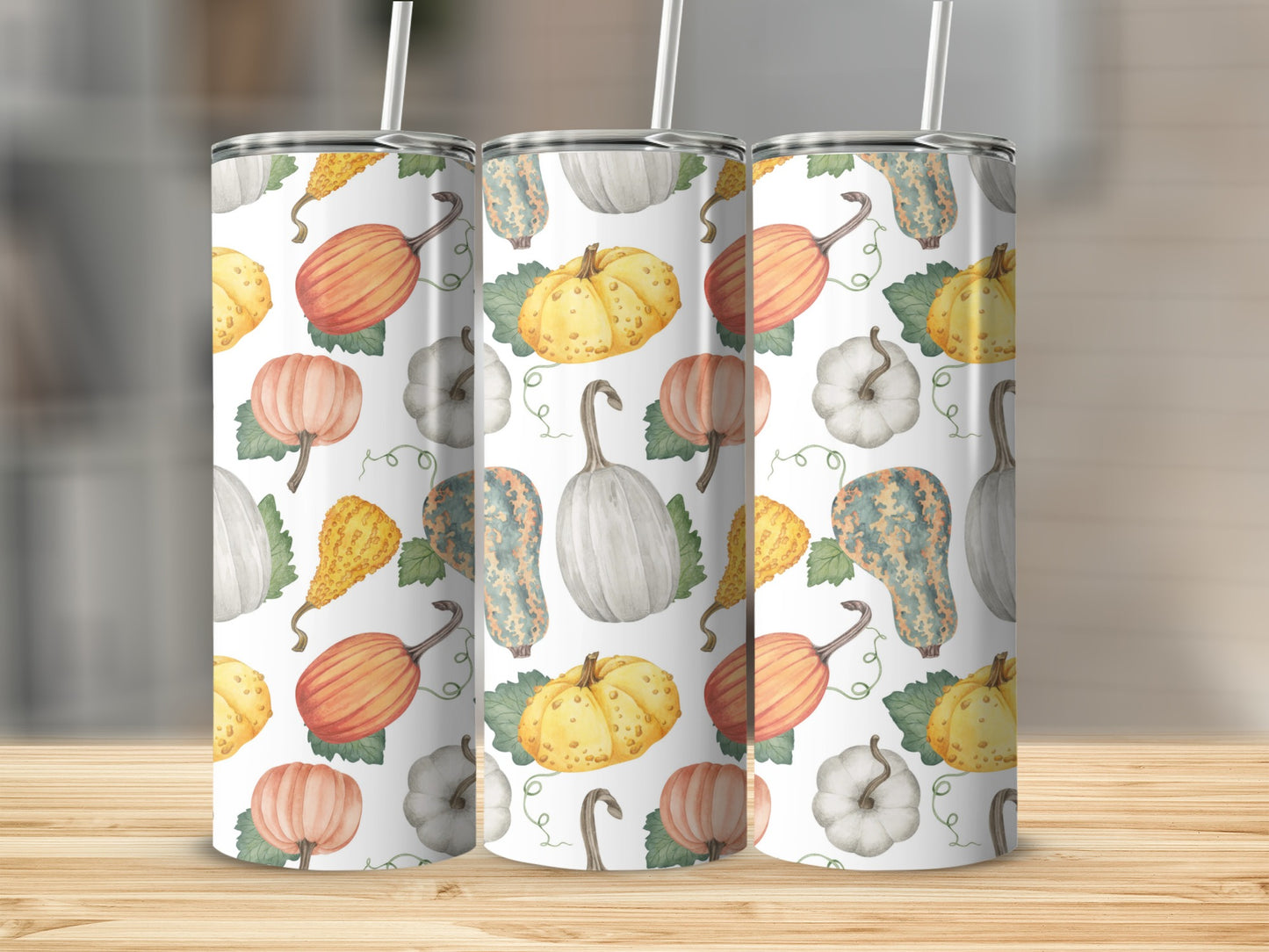 Pumpkin and gourd pattern on three white tumblers with straws.