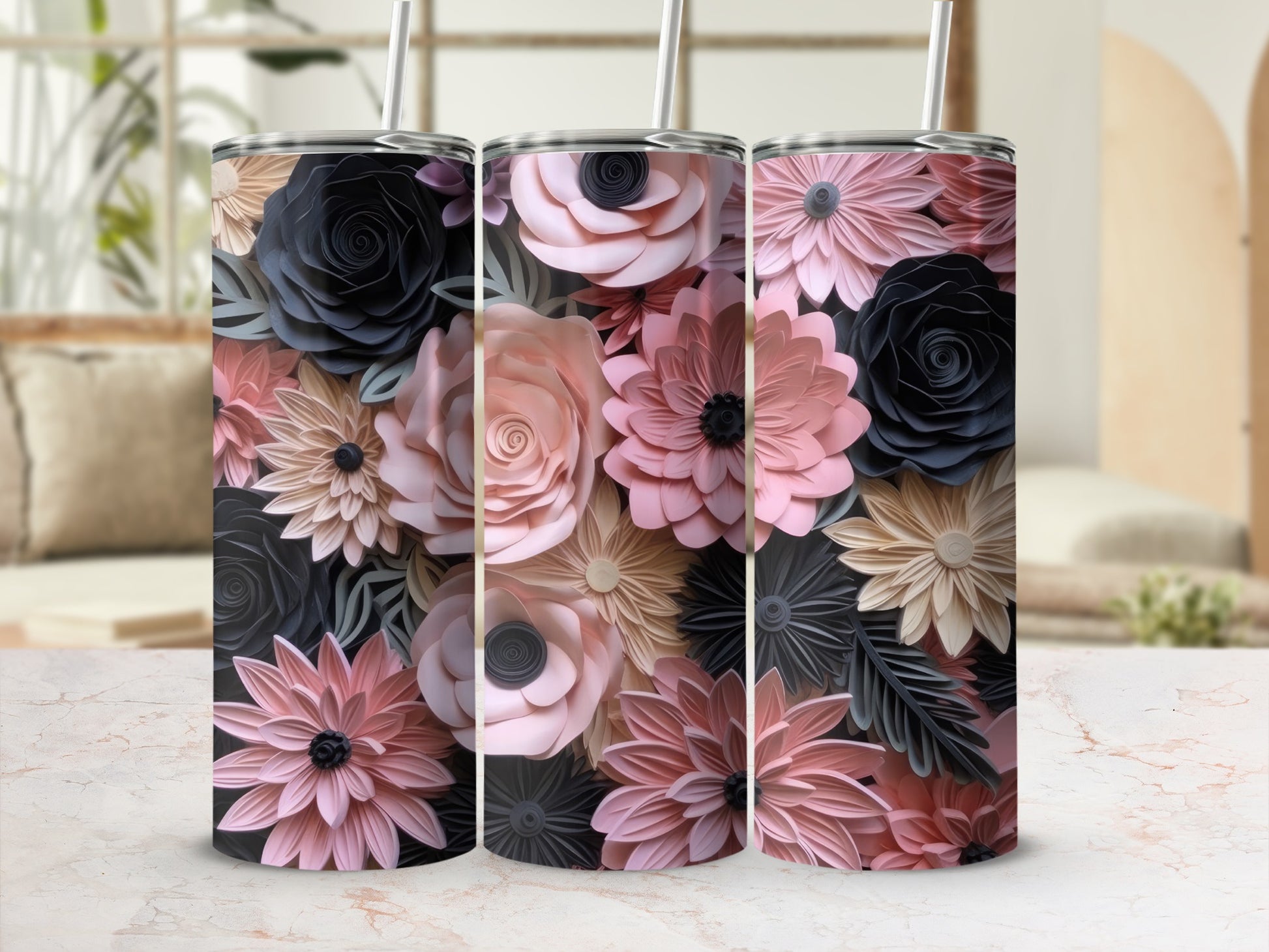 Three floral print tumblers with straws on a marbled surface.