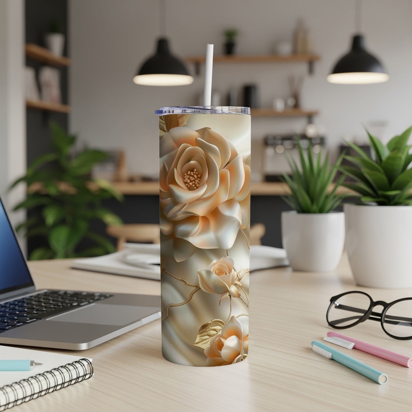 Tall tumbler with rose floral design and white straw on a desk.