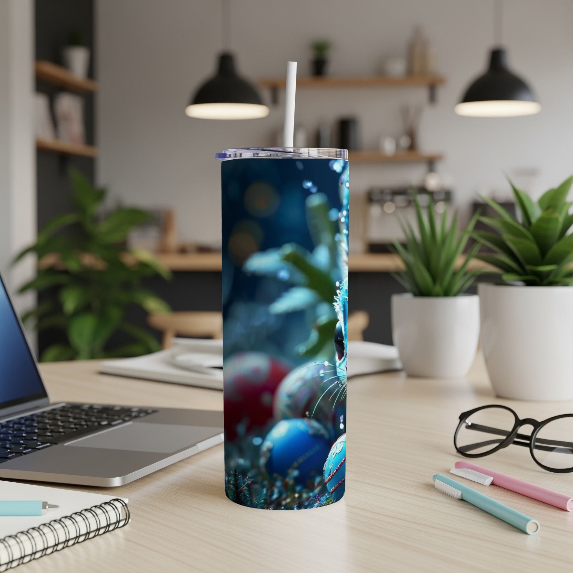Blue tumbler with a cat and ornaments on a desk.