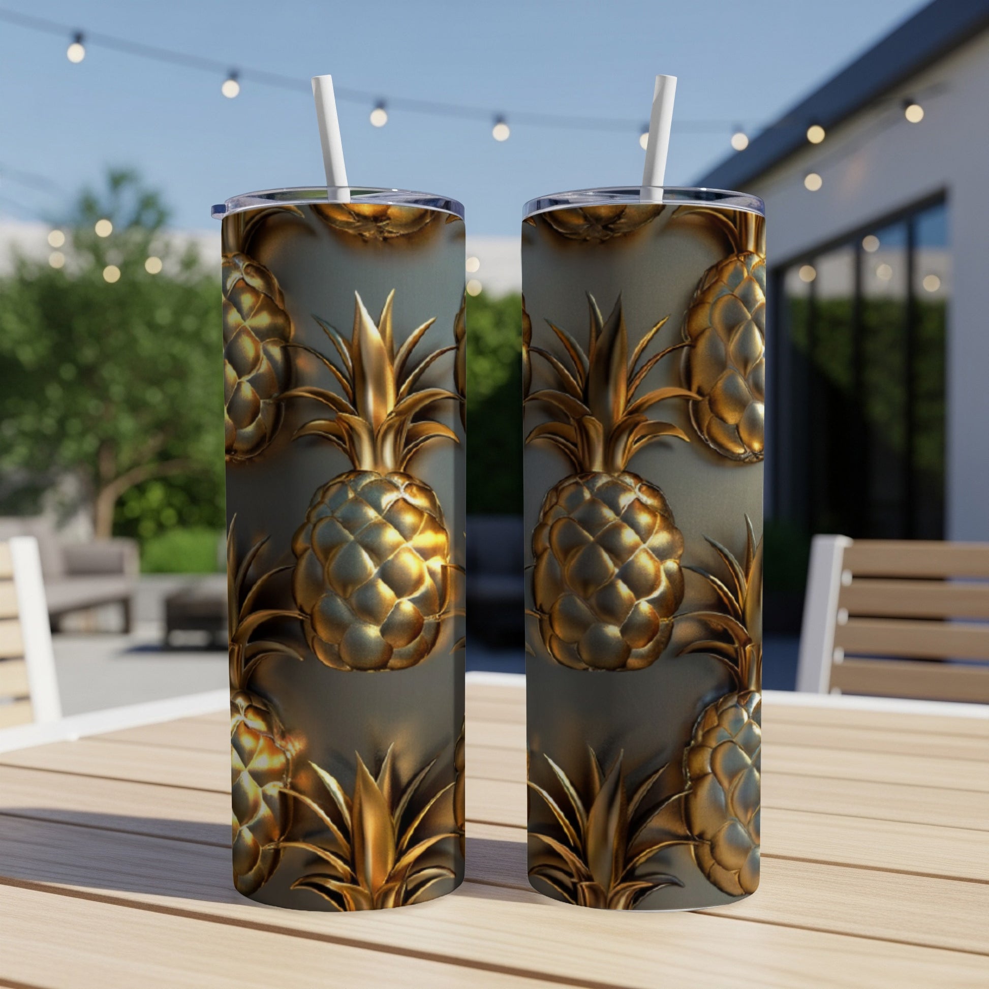 Two gold pineapple tumblers with straws on a wooden table outdoors.