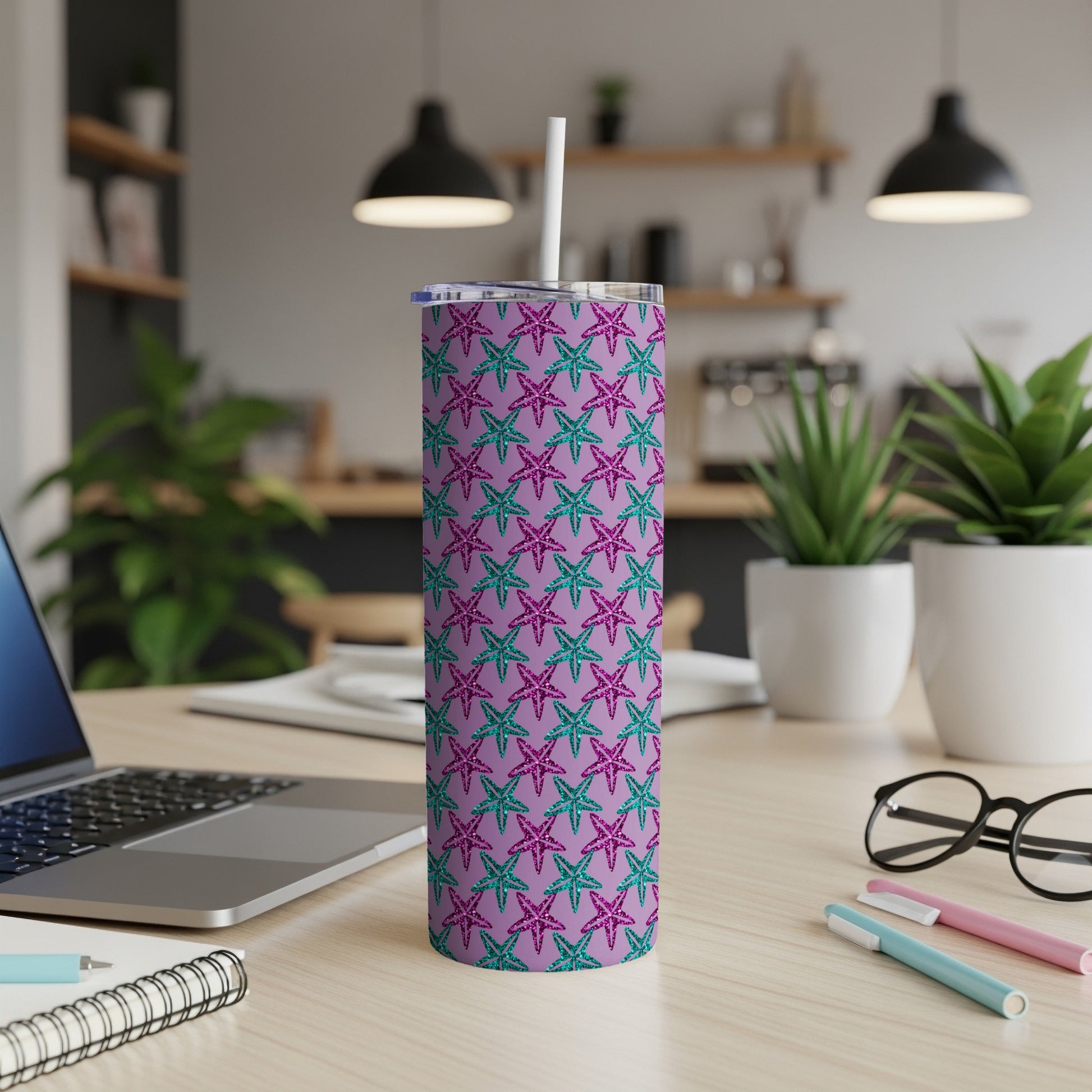Tumbler with purple and teal starfish pattern and white straw on a desk.
