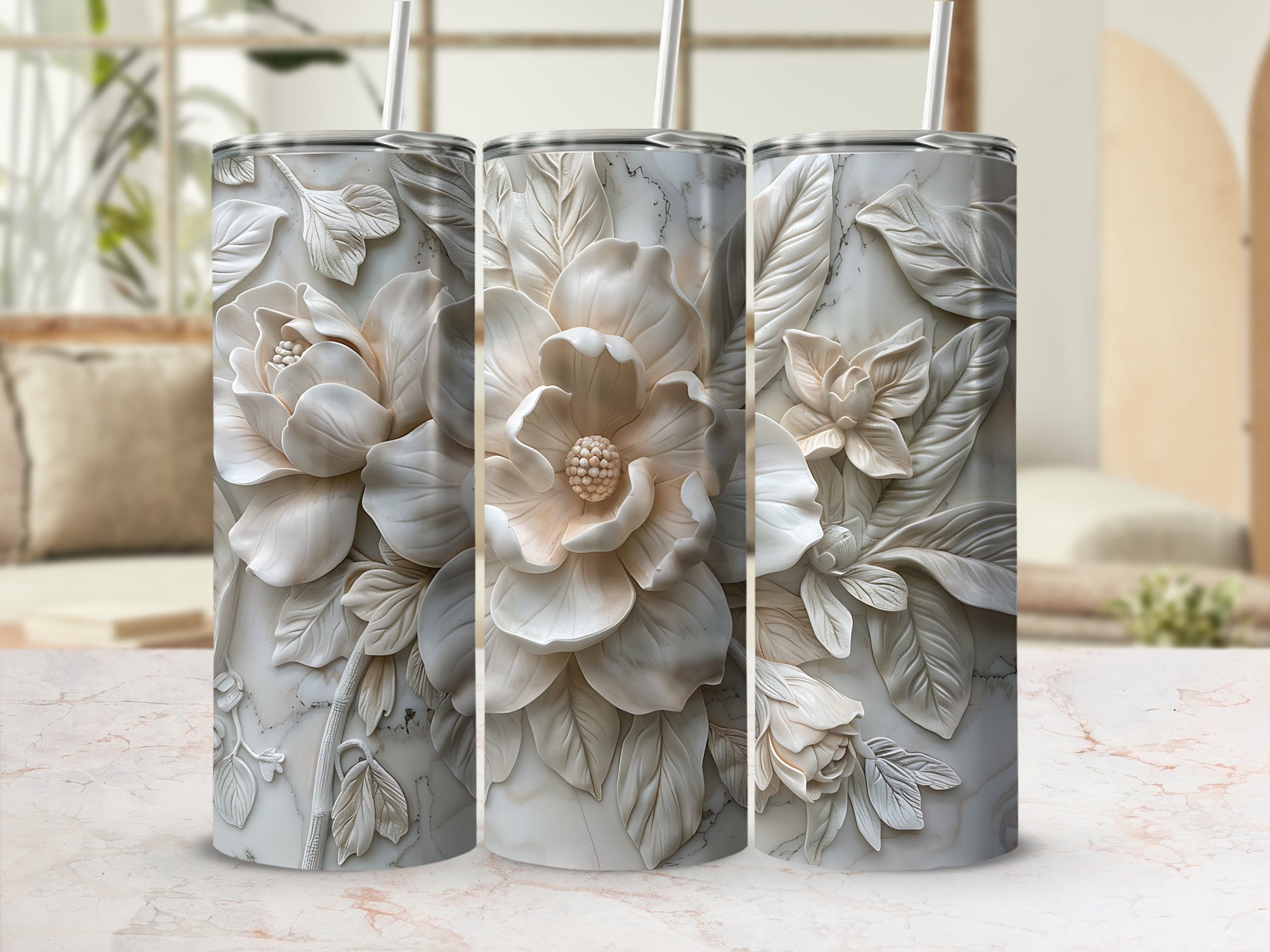 Three tumblers with embossed floral designs and straws on a textured surface.