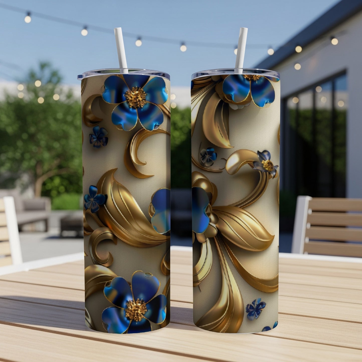 Two tall tumblers with golden floral and blue flower designs on a patio table.