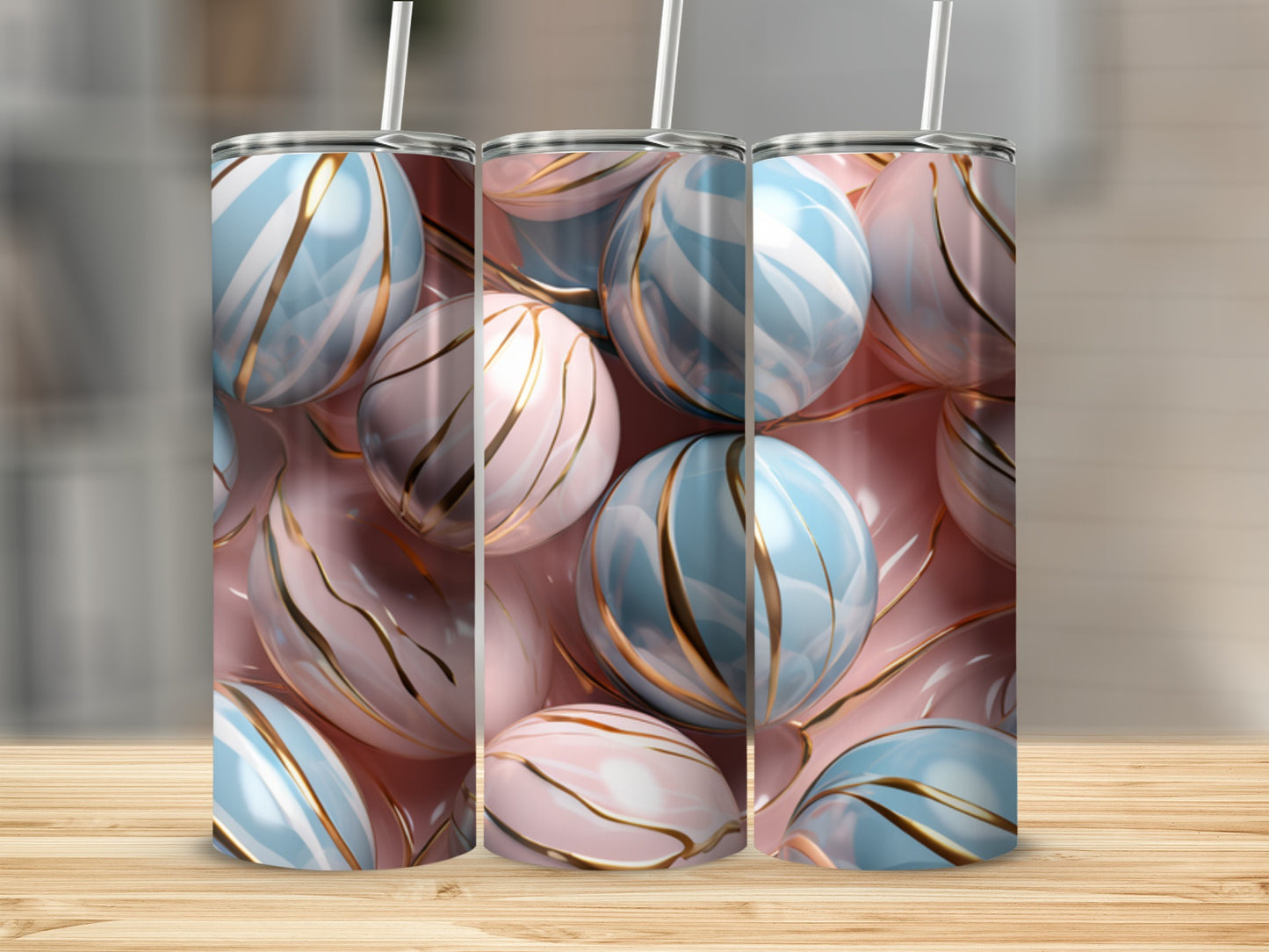Three tumblers with pastel pink and blue stripes and gold accents on a wooden surface.