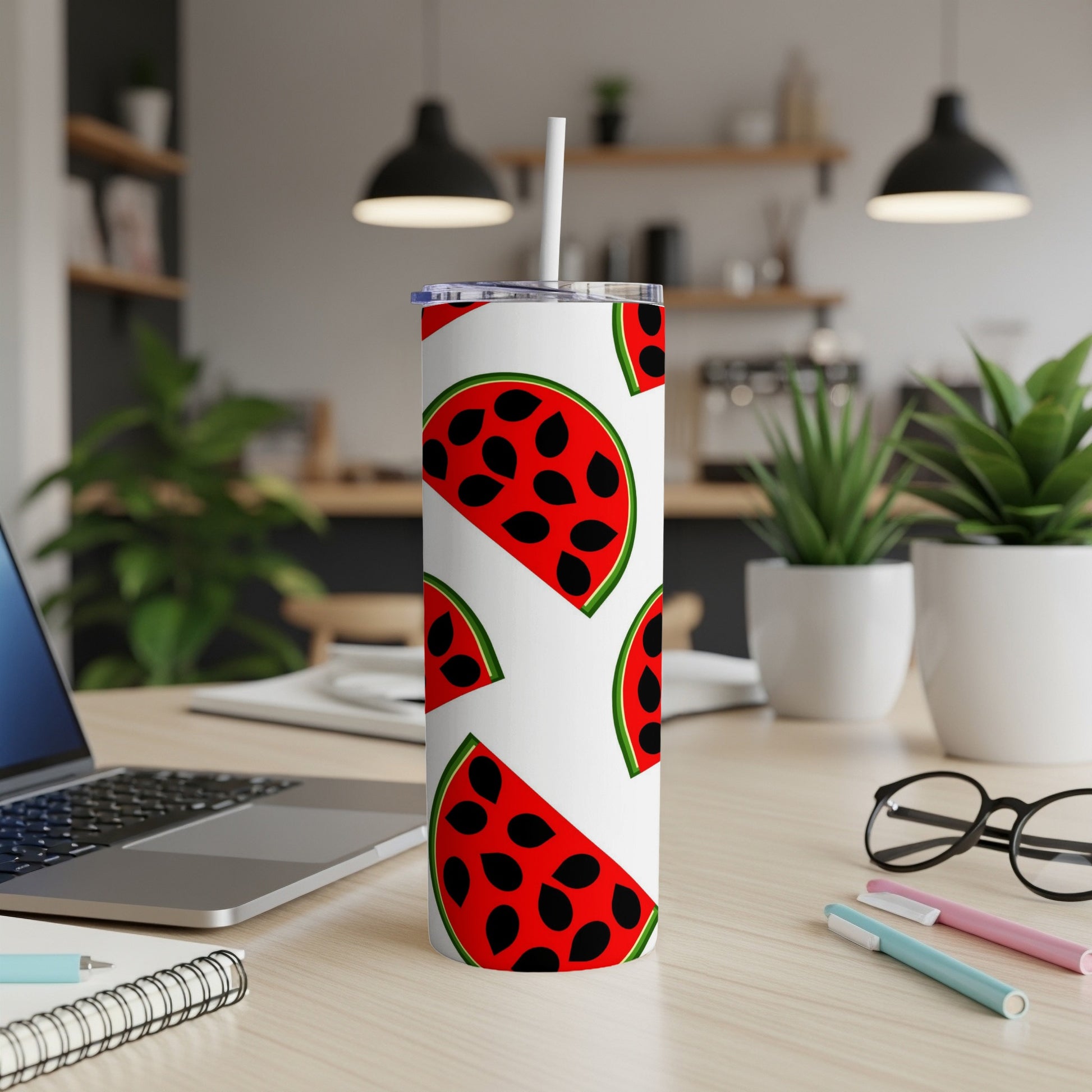 White tumbler with watermelon slices and black seeds, on a desk.