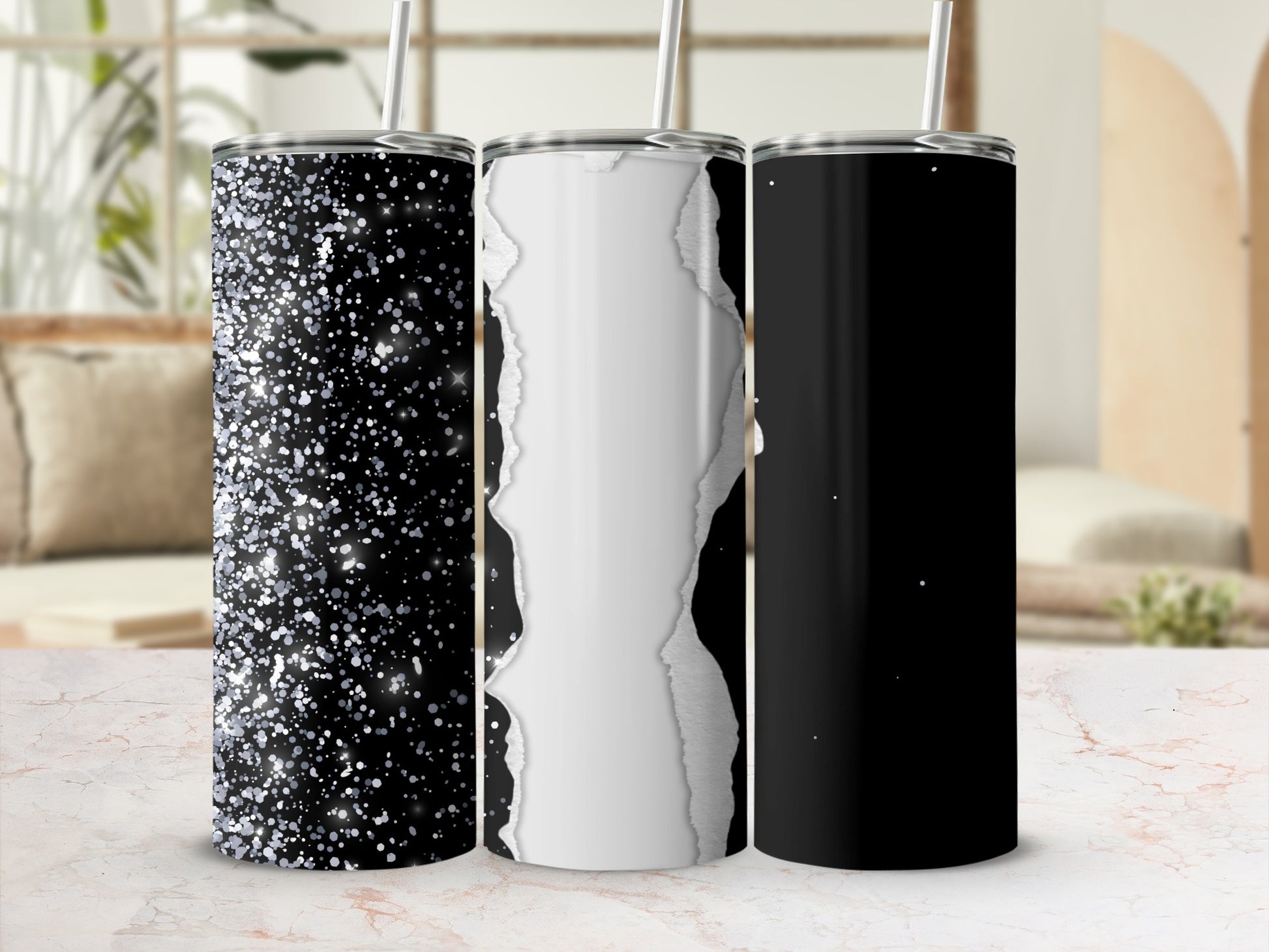 Three glitter and torn paper designs on black tumblers with straws.