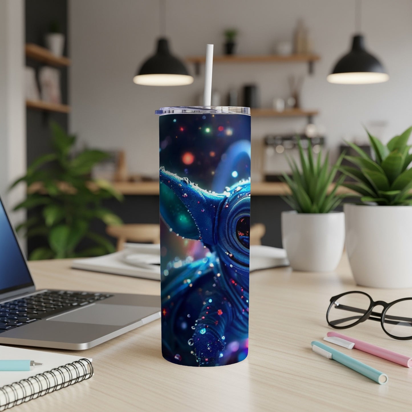 Blue tumbler with a stylized alien character and colorful glitter accents.