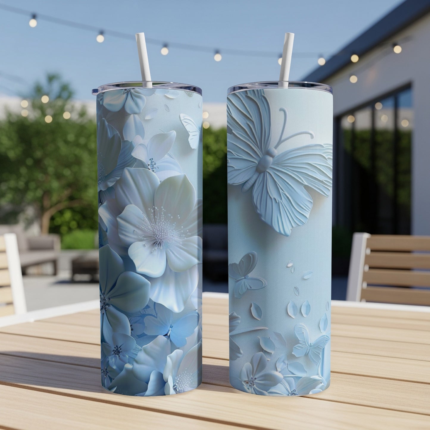 Two light blue tumblers with raised floral and butterfly designs on a table.