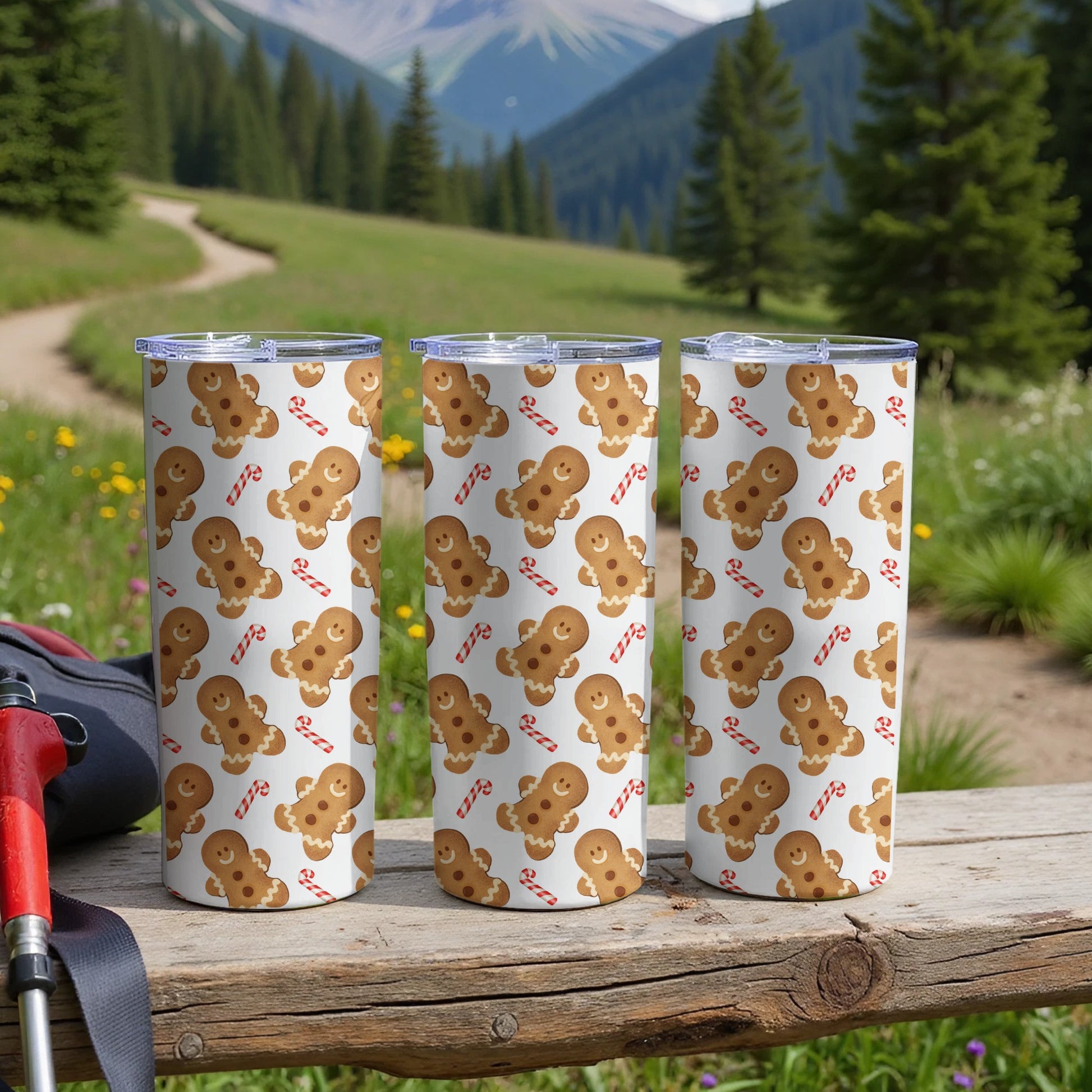 Three gingerbread man and candy cane pattern tumblers on a wooden surface.
