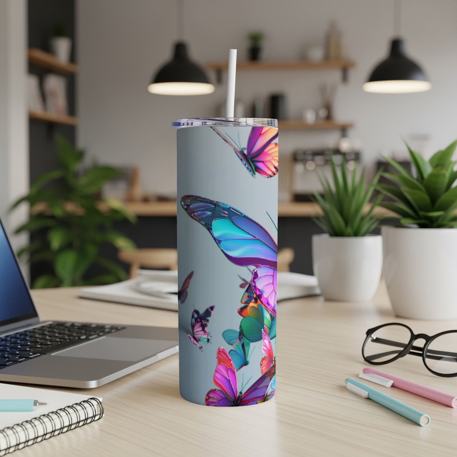 Gray tumbler with colorful butterflies, a laptop, and office supplies.