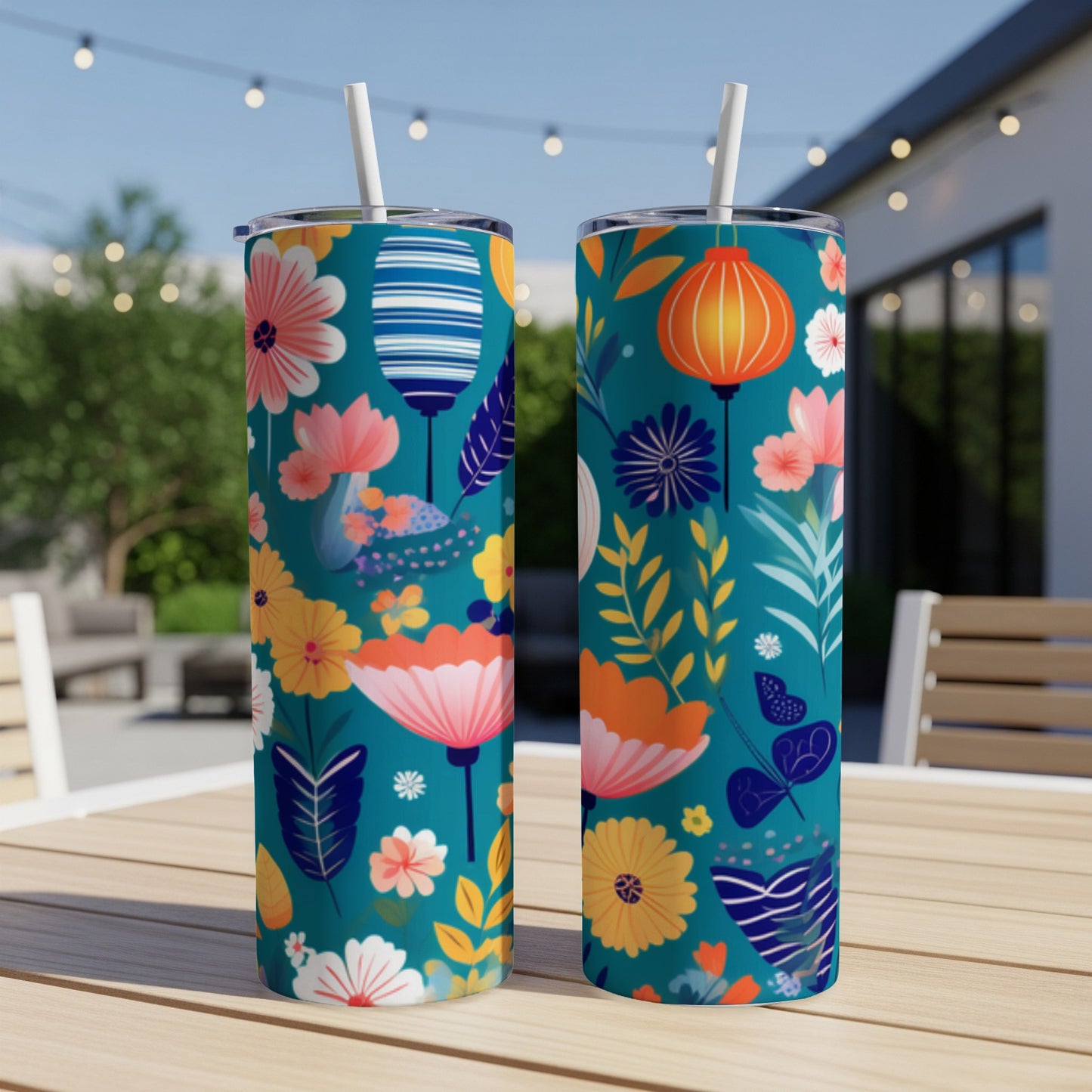 Two teal tumblers with floral and lantern patterns sit on a table.
