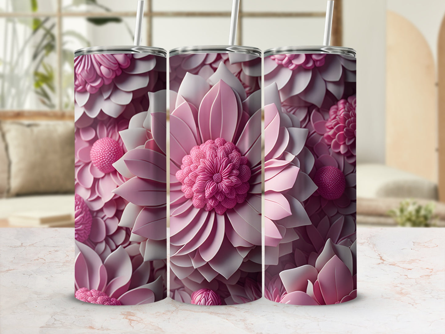 Three pink floral tumblers with straws displayed on a marble surface.