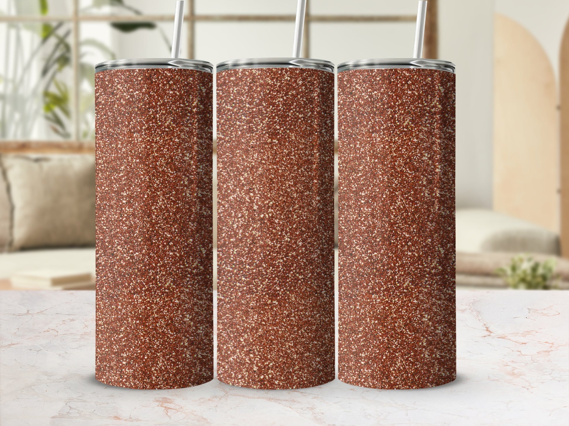 Three tall, glittery copper tumblers with white straws against a blurred home interior background.