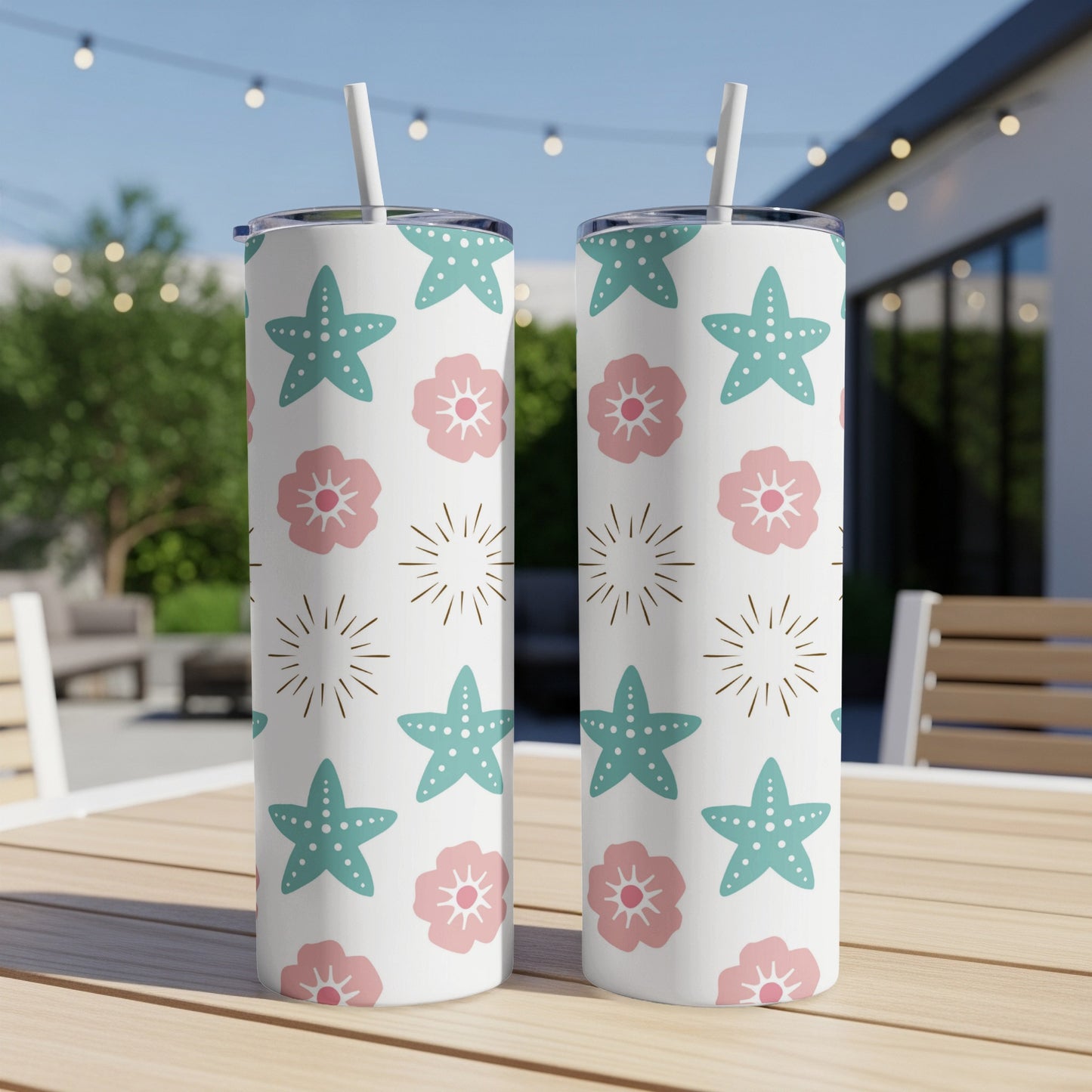Two white tumblers with starfish and flower pattern on outdoor table.