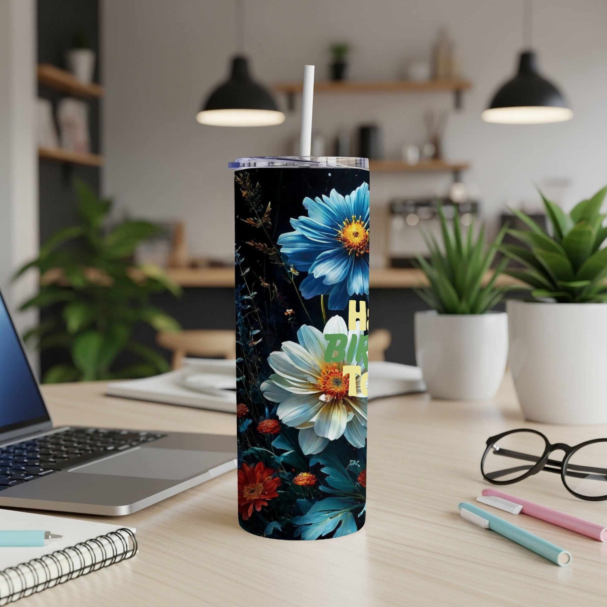 Floral tumbler with "Happy Birthday" text on a desk with laptop and pens.