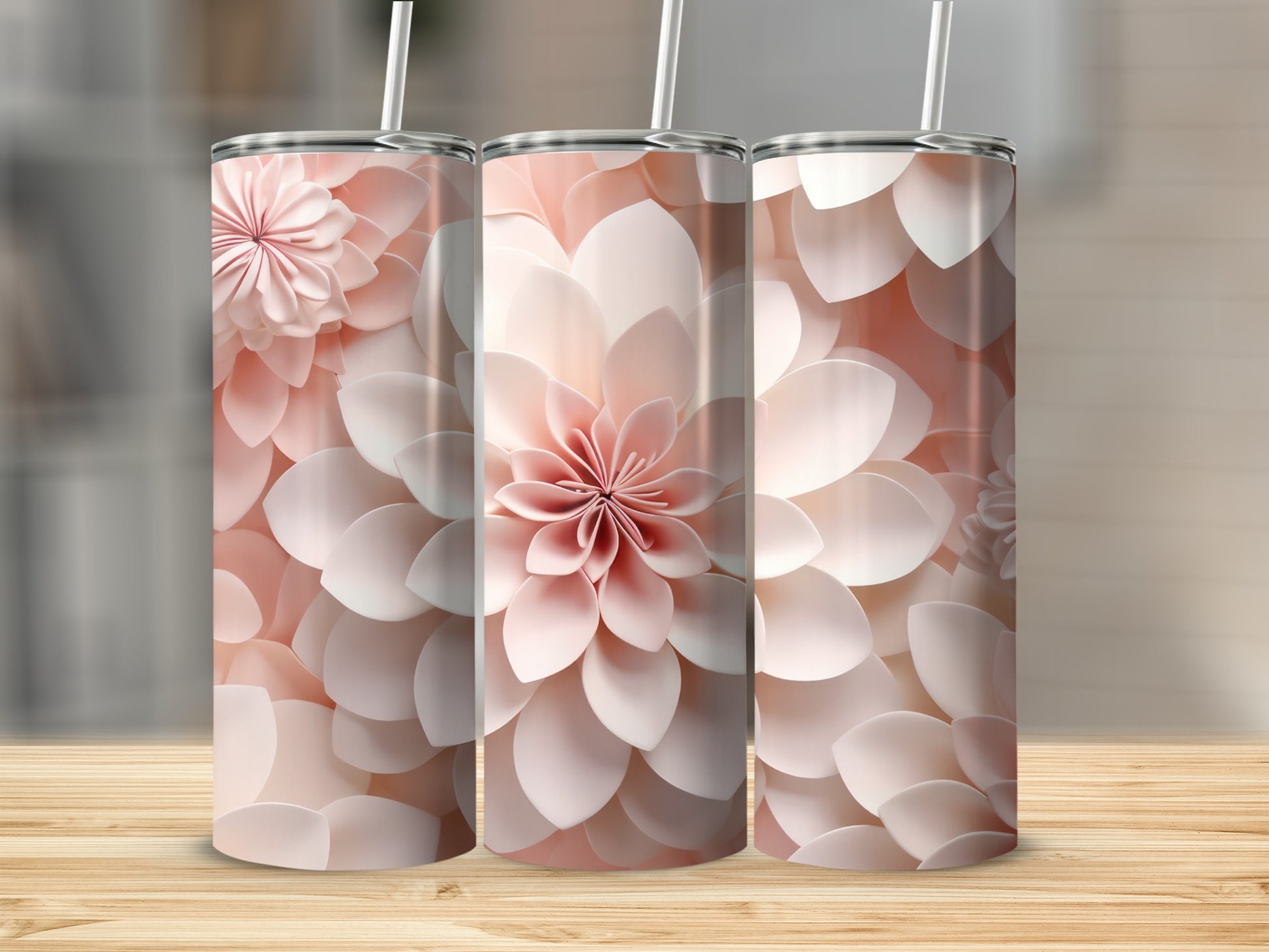Three pink floral tumblers with straws on a wooden surface.
