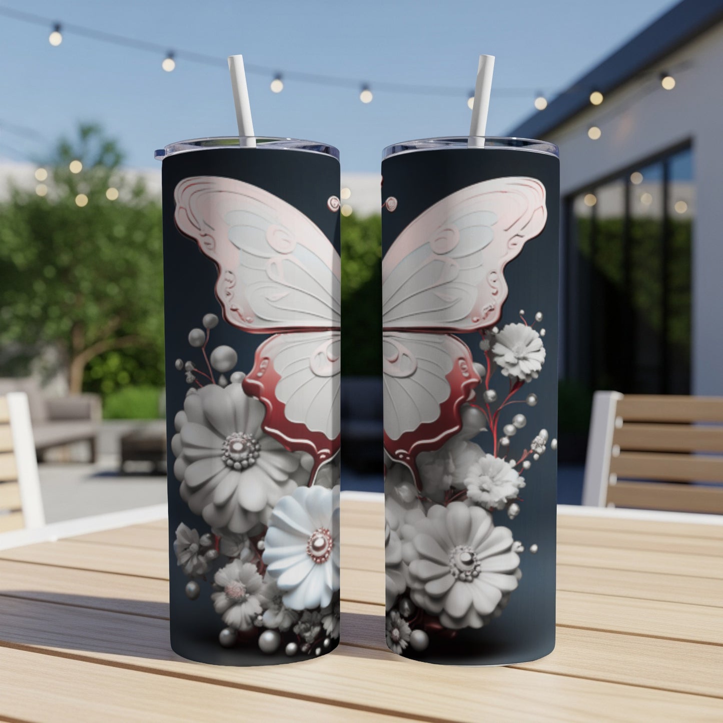 Two tumblers with a butterfly and floral design sit on a wooden table outdoors.