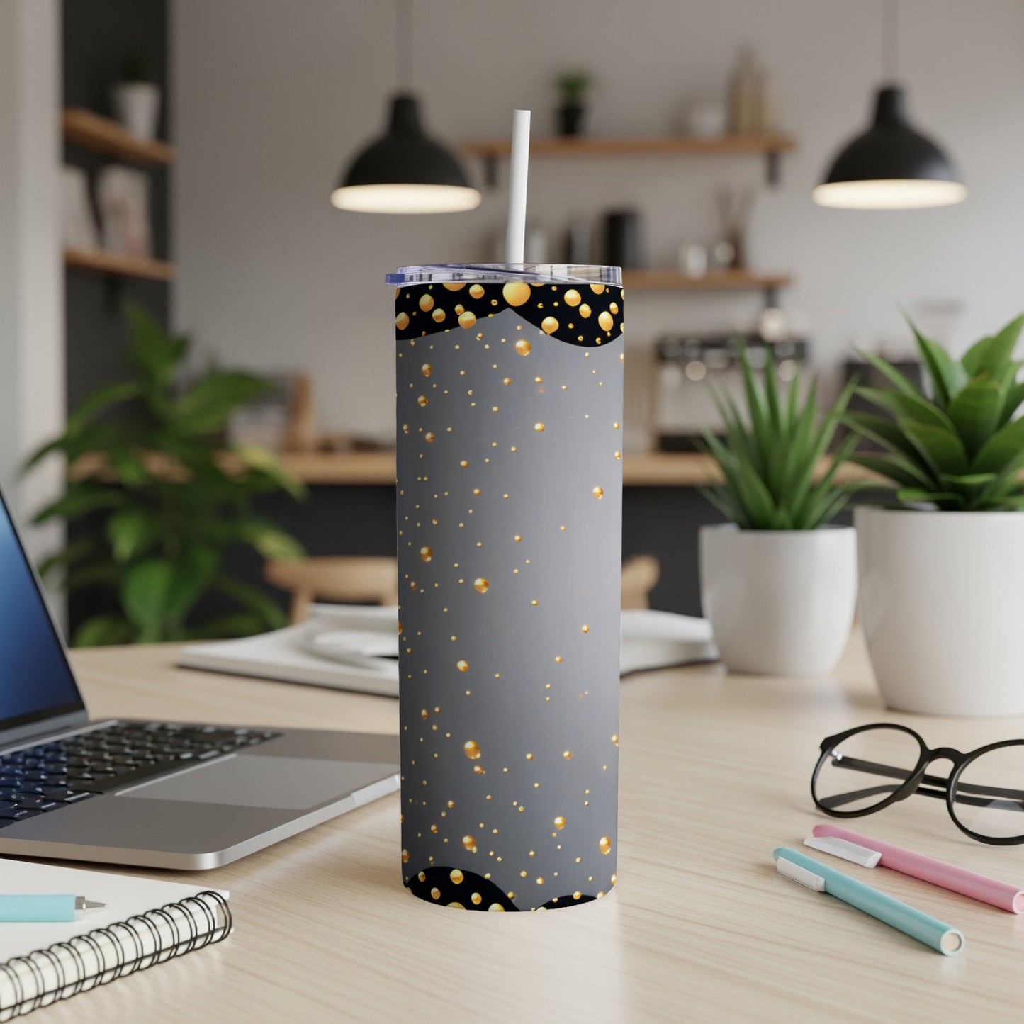 Gray tumbler with gold bubbles design on a desk with laptop and pens.