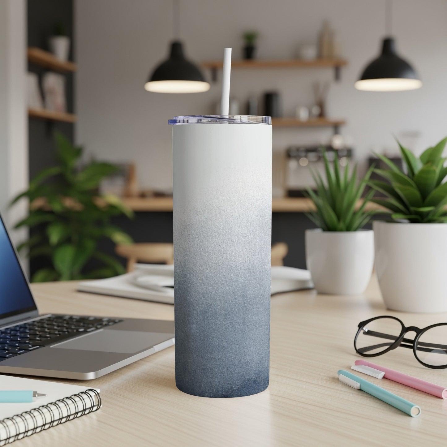 White and blue gradient skinny tumbler with a straw on a desk.