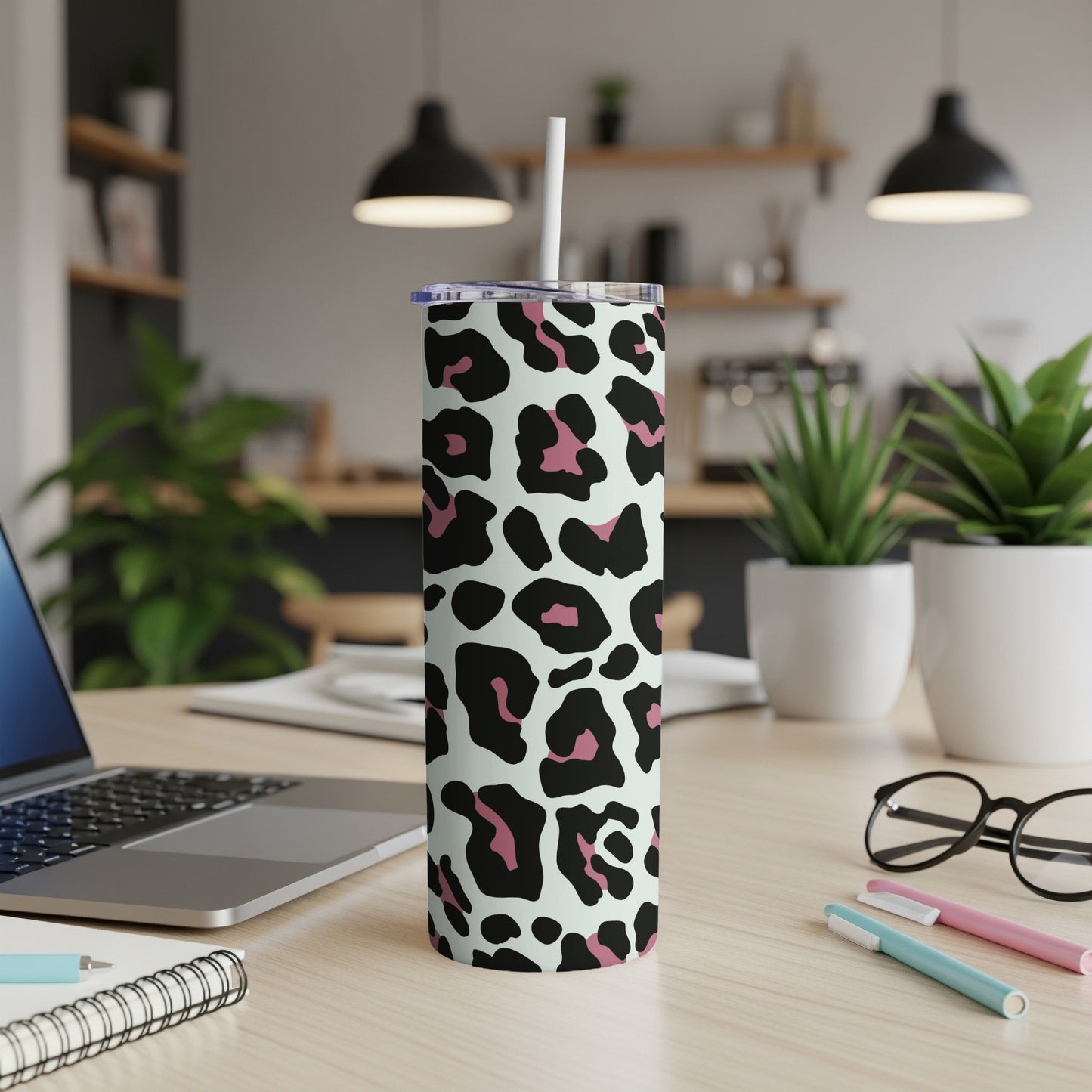 Leopard print insulated tumbler with straw on a desk.