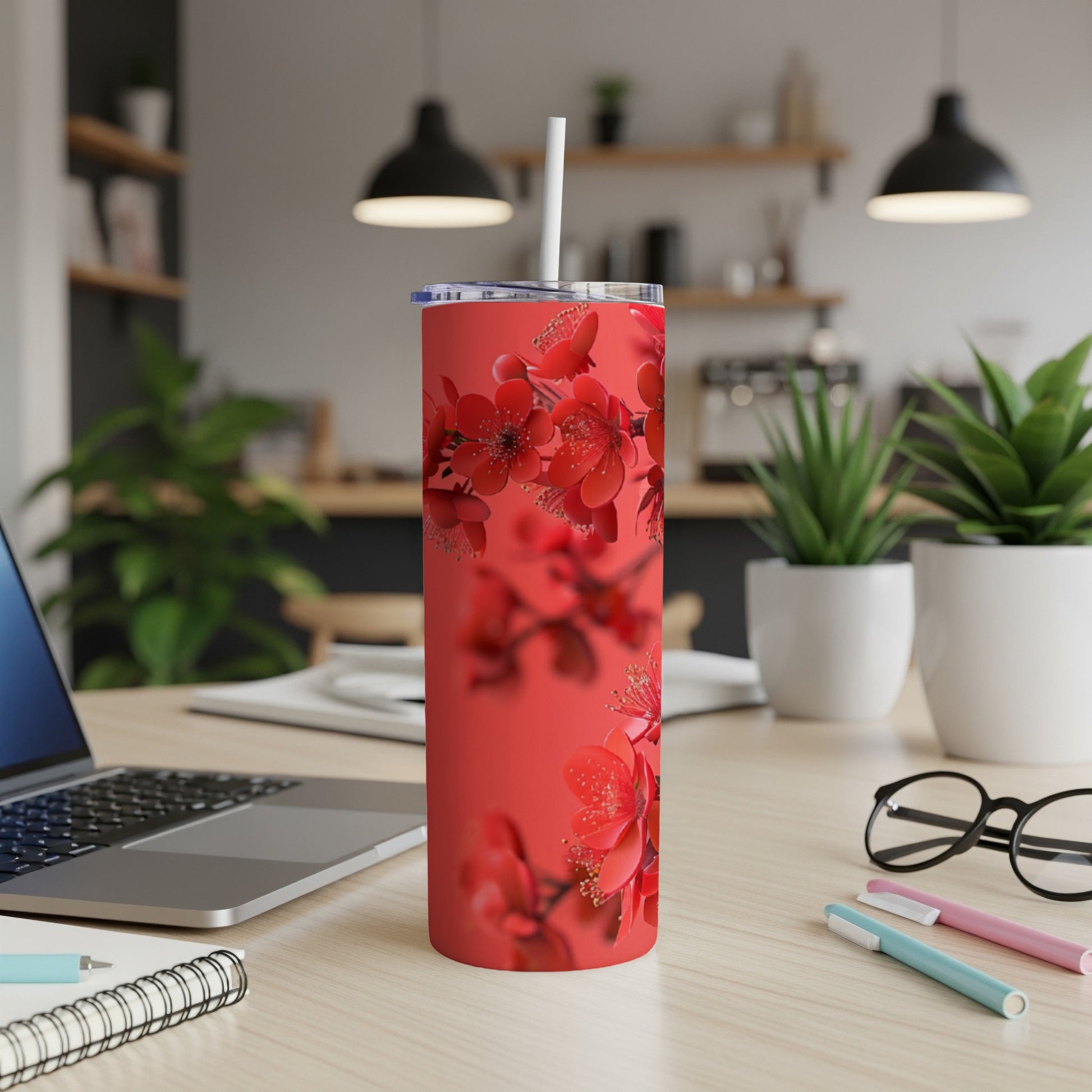 Red floral skinny tumbler with straw on a desk.