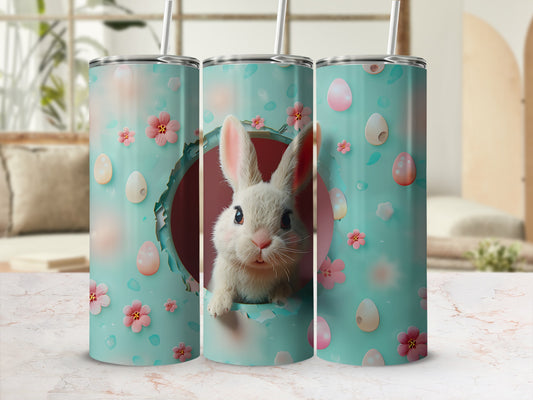 Easter bunny peeking out of a mint green tumbler with pink flowers and eggs.
