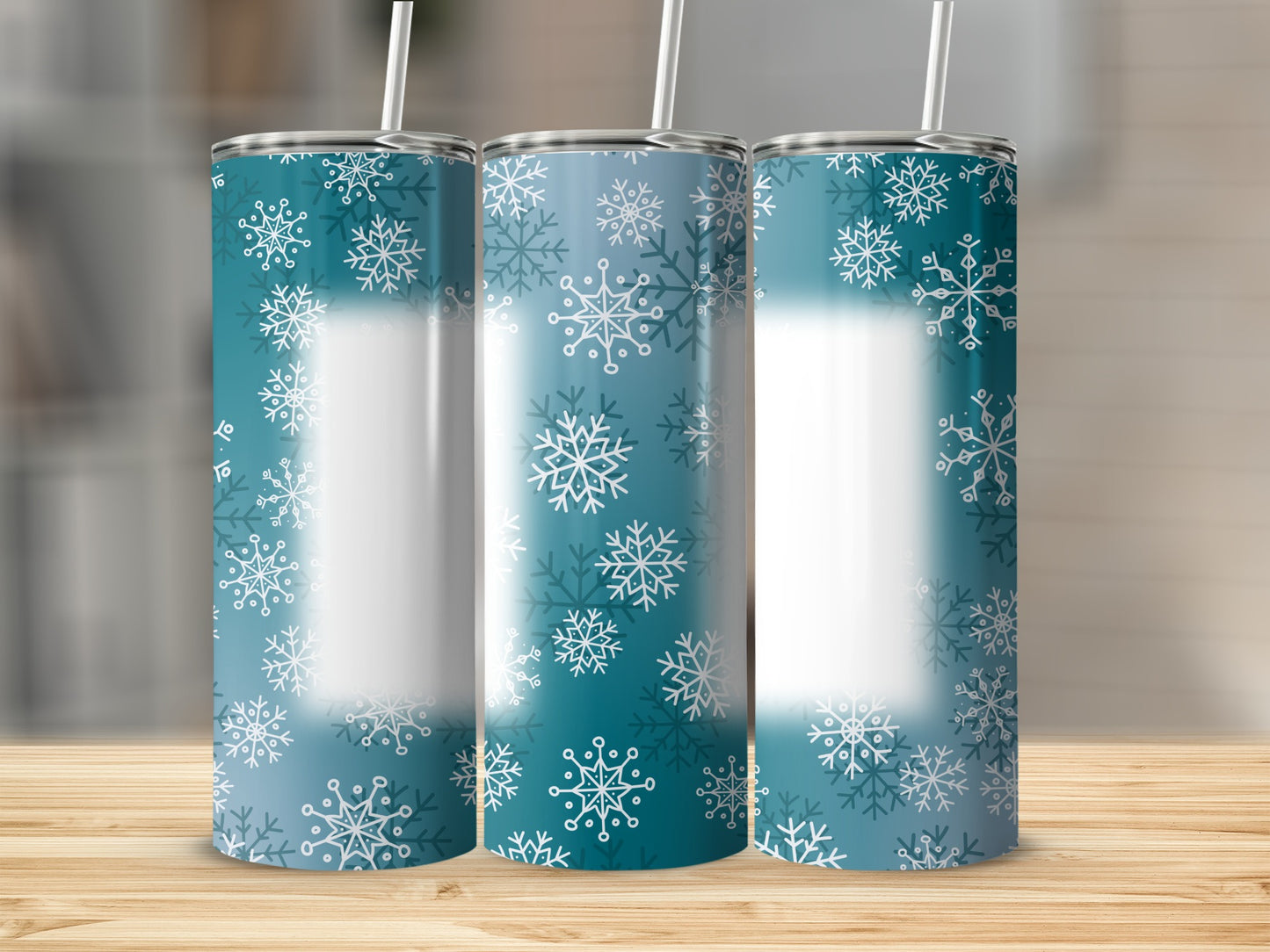 Three teal tumblers with white snowflake patterns stand on a wooden surface.