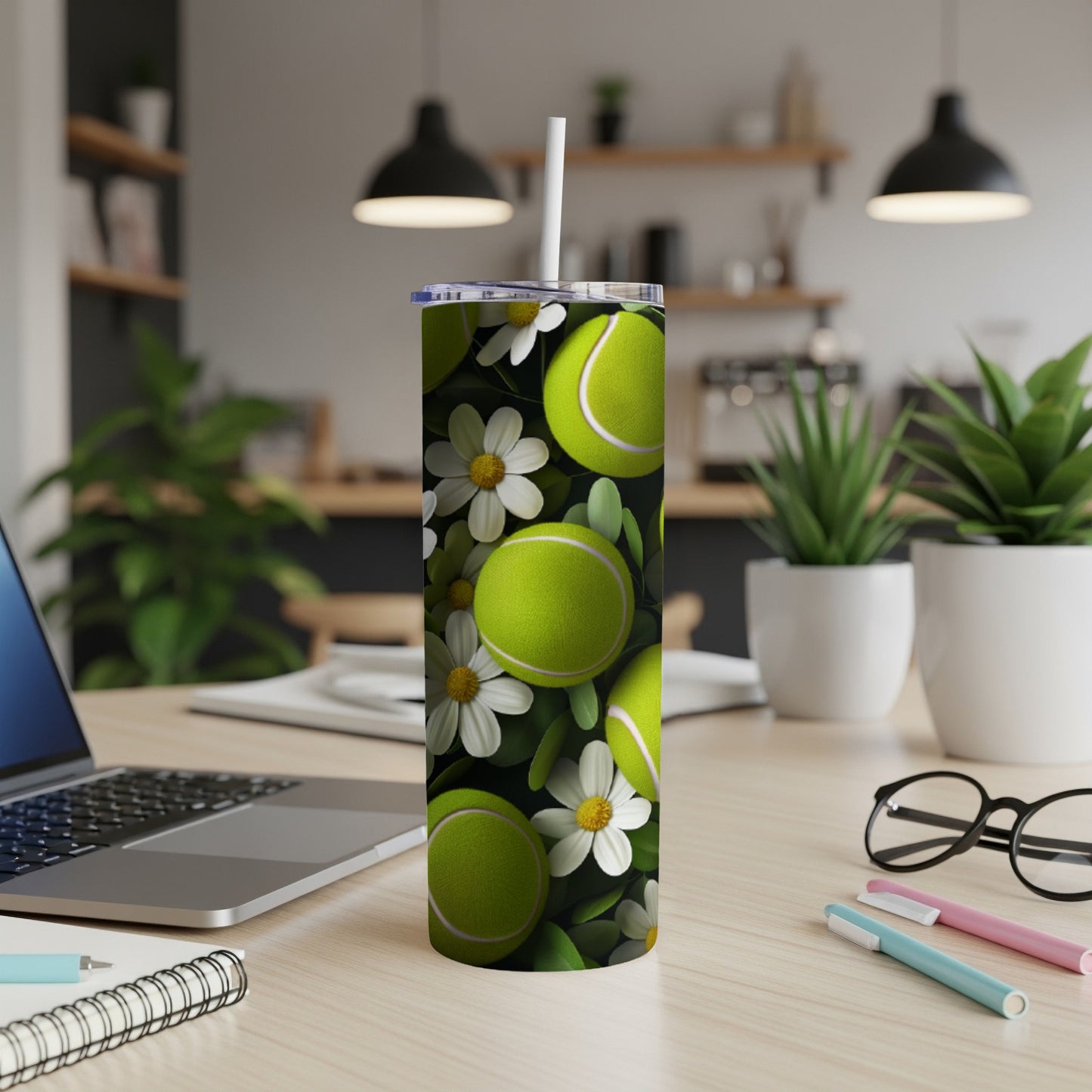 Tumbler with tennis balls and daisies design, with a straw.