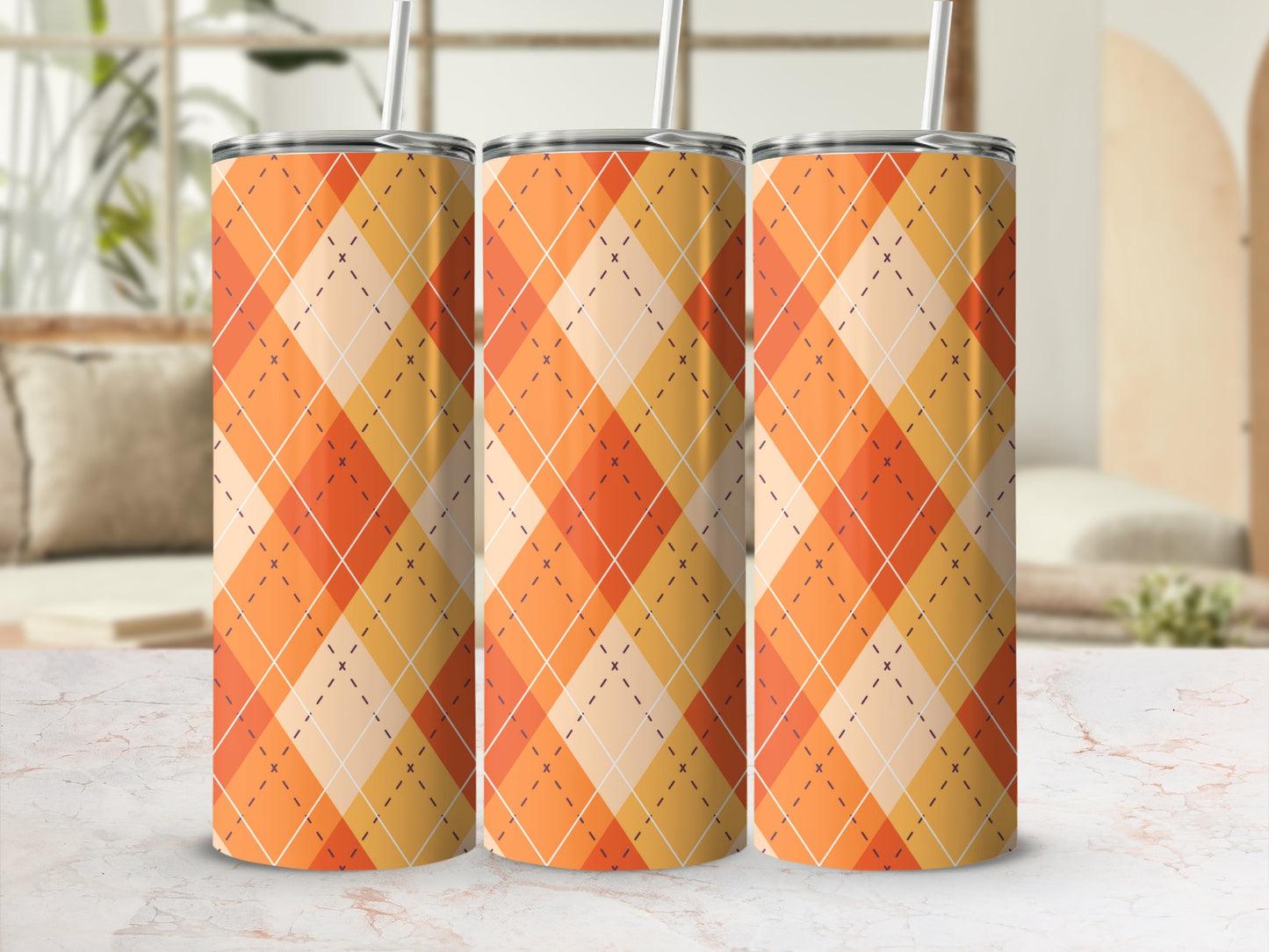 Three orange argyle pattern tumblers with straws on a marble surface.