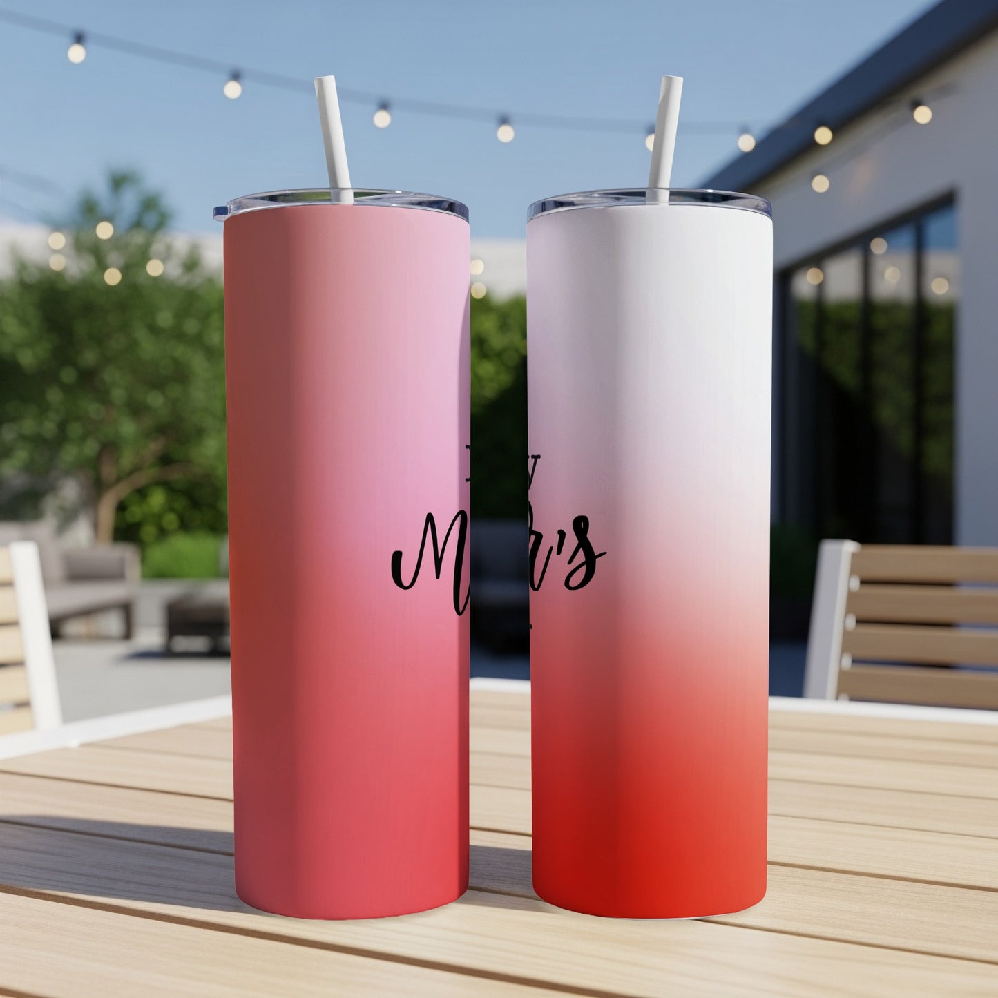 Two pink and red gradient tumblers with straws sit on a table.