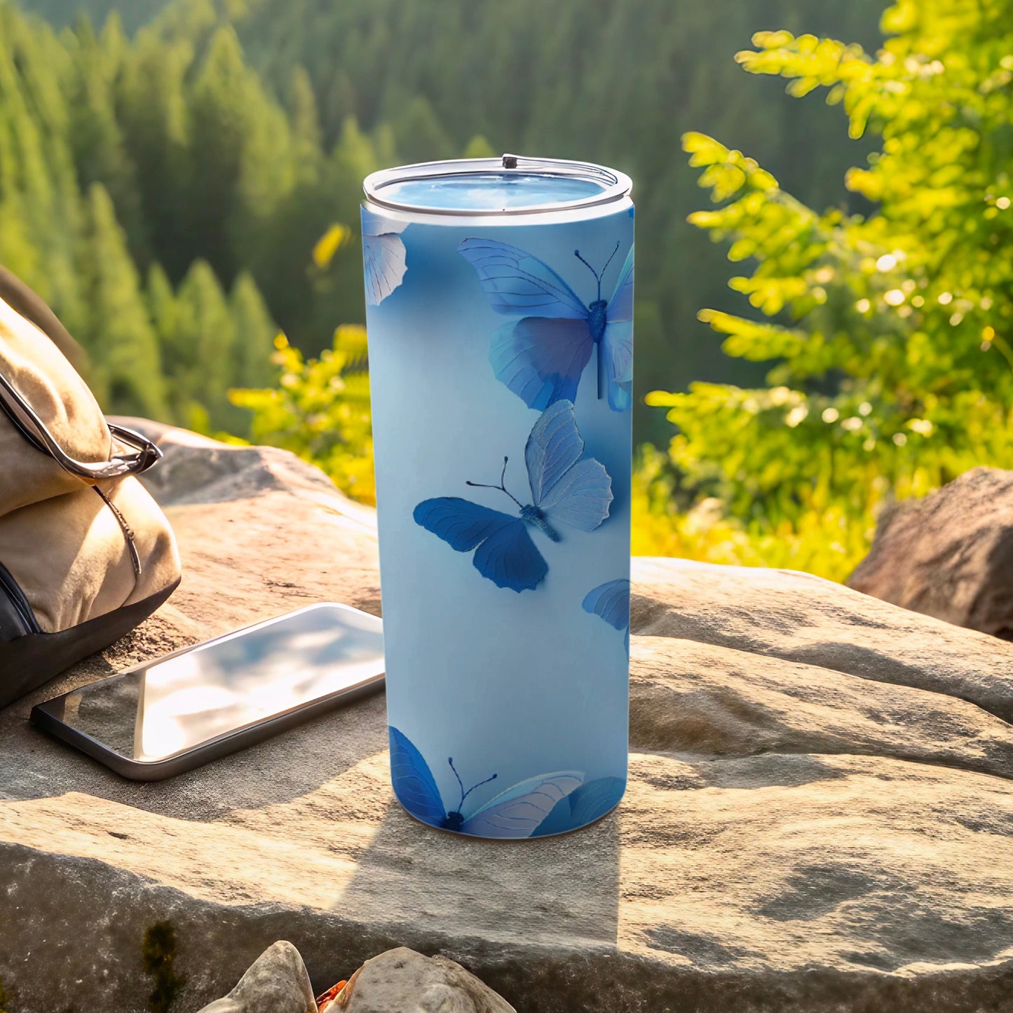Light blue tumbler with butterfly pattern, resting on rocks outdoors.
