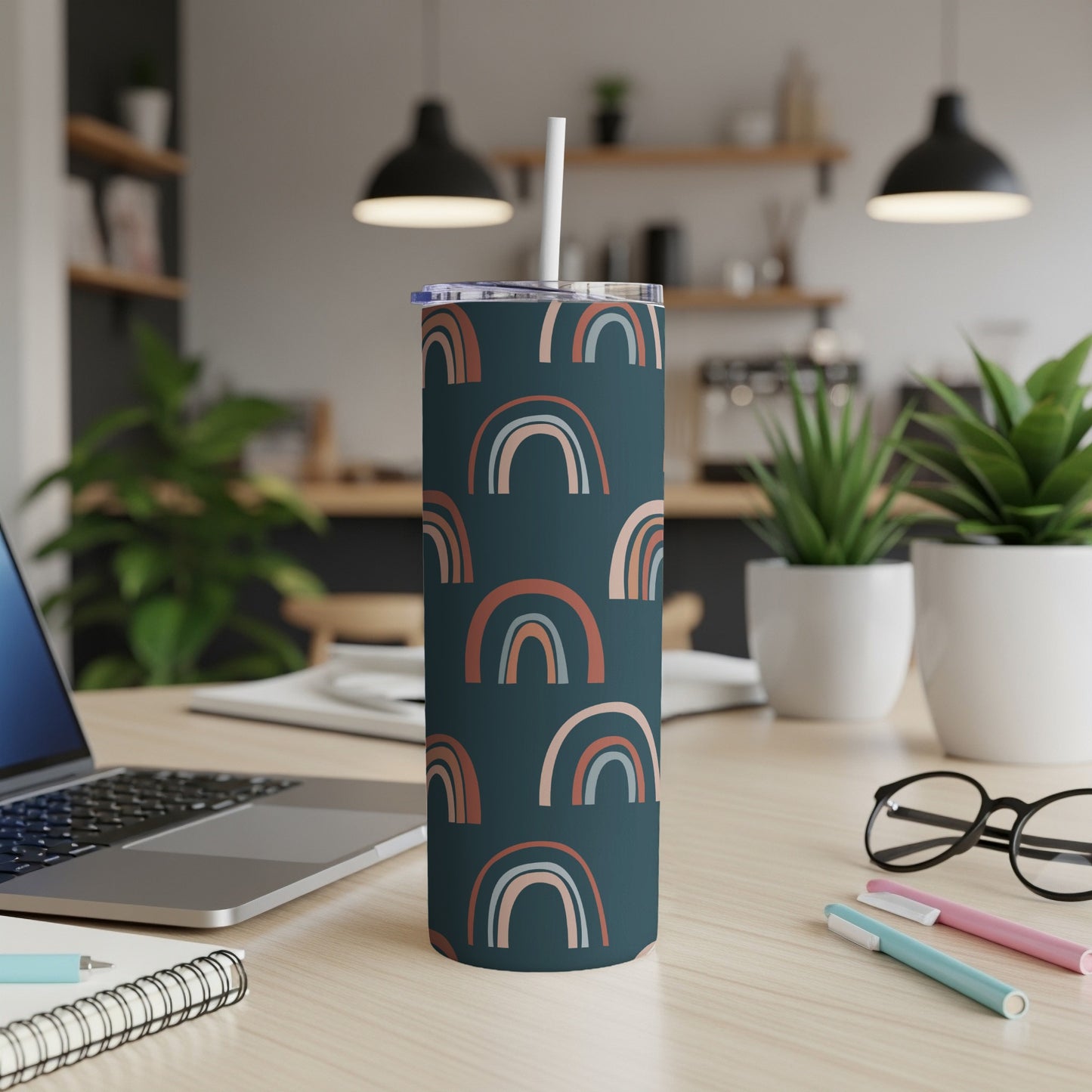 Dark teal tumbler with scattered muted rainbow pattern and white straw.