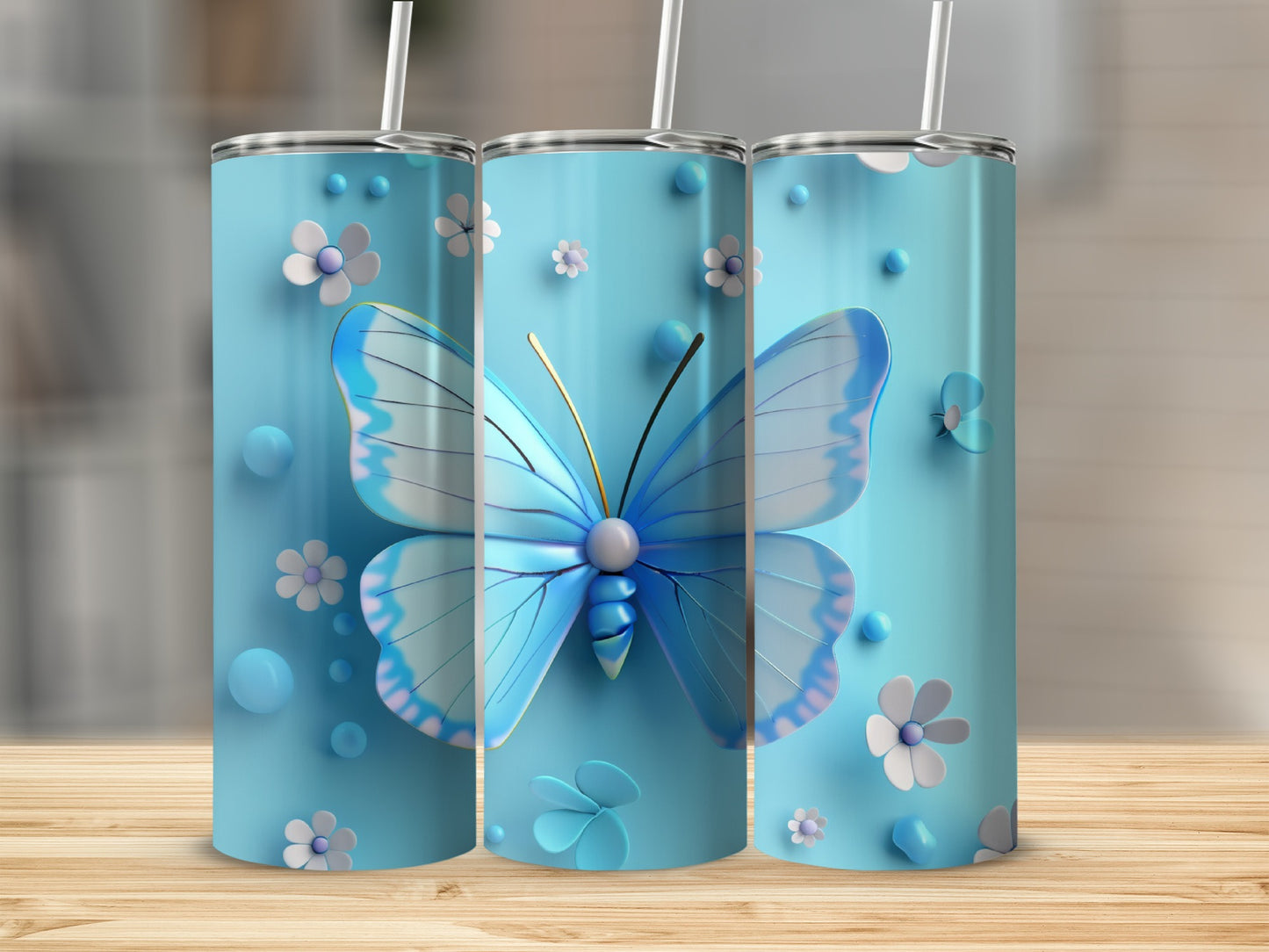 Three blue tumblers with butterflies and flowers, displayed on a wooden surface.