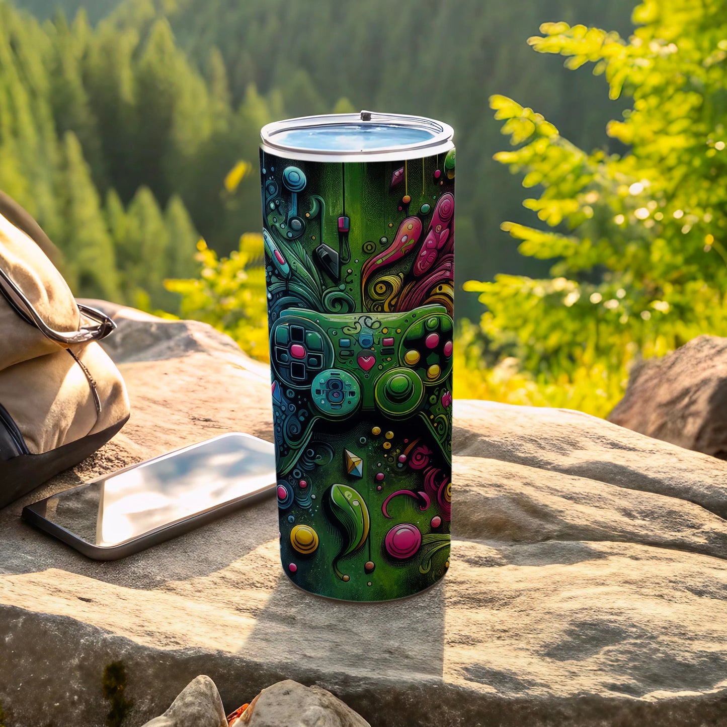 Green tumbler with colorful video game controller design rests on rock.