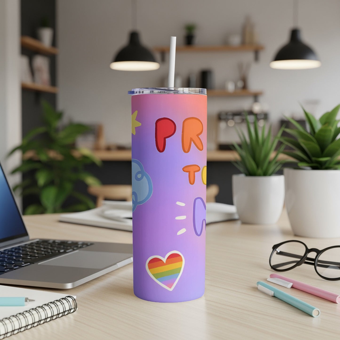 Purple tumbler with rainbow heart and "Pride" text, on a desk.