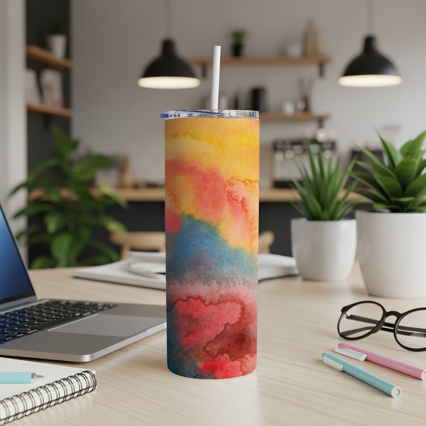 Colorful abstract art tumbler with straw on a desk.