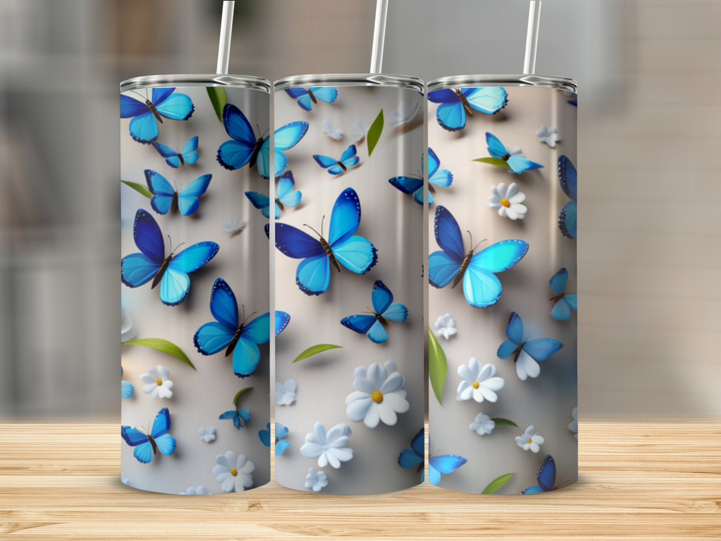 Three tumblers with blue butterflies and white flowers on a wood surface.