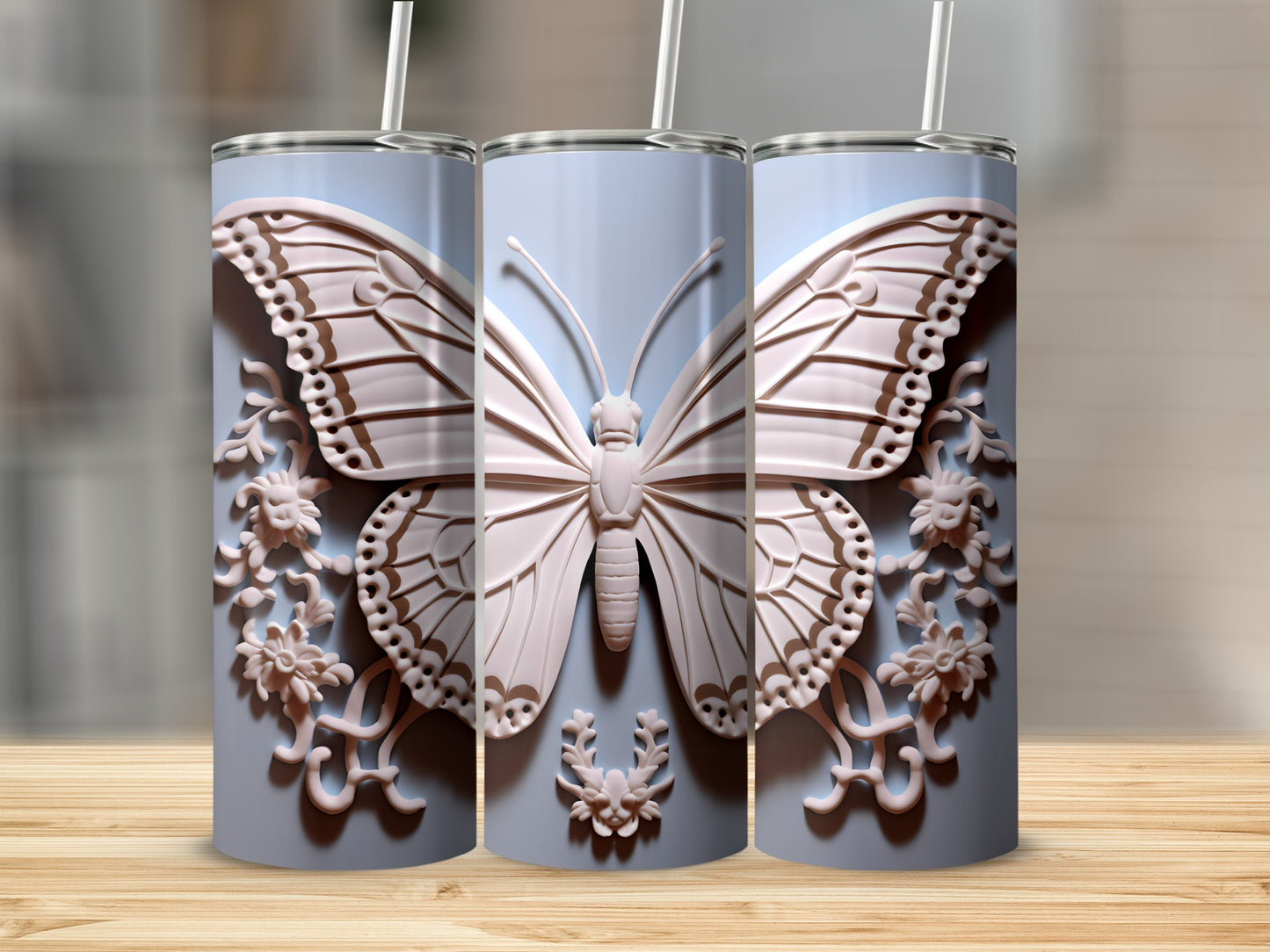 Three pastel blue tumblers with intricate butterfly and floral embossed designs.