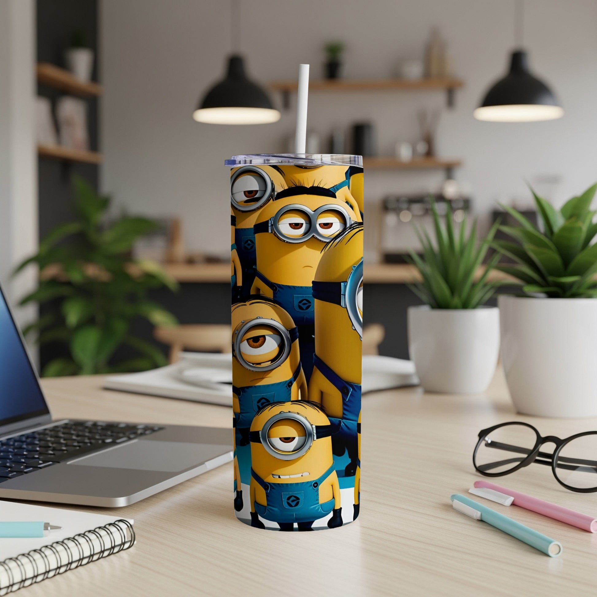 Minions on a blue and yellow tumbler with a straw, on a desk.