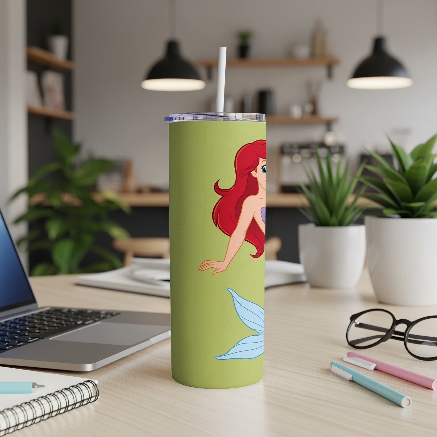 Ariel the mermaid on a light green tumbler with a straw.
