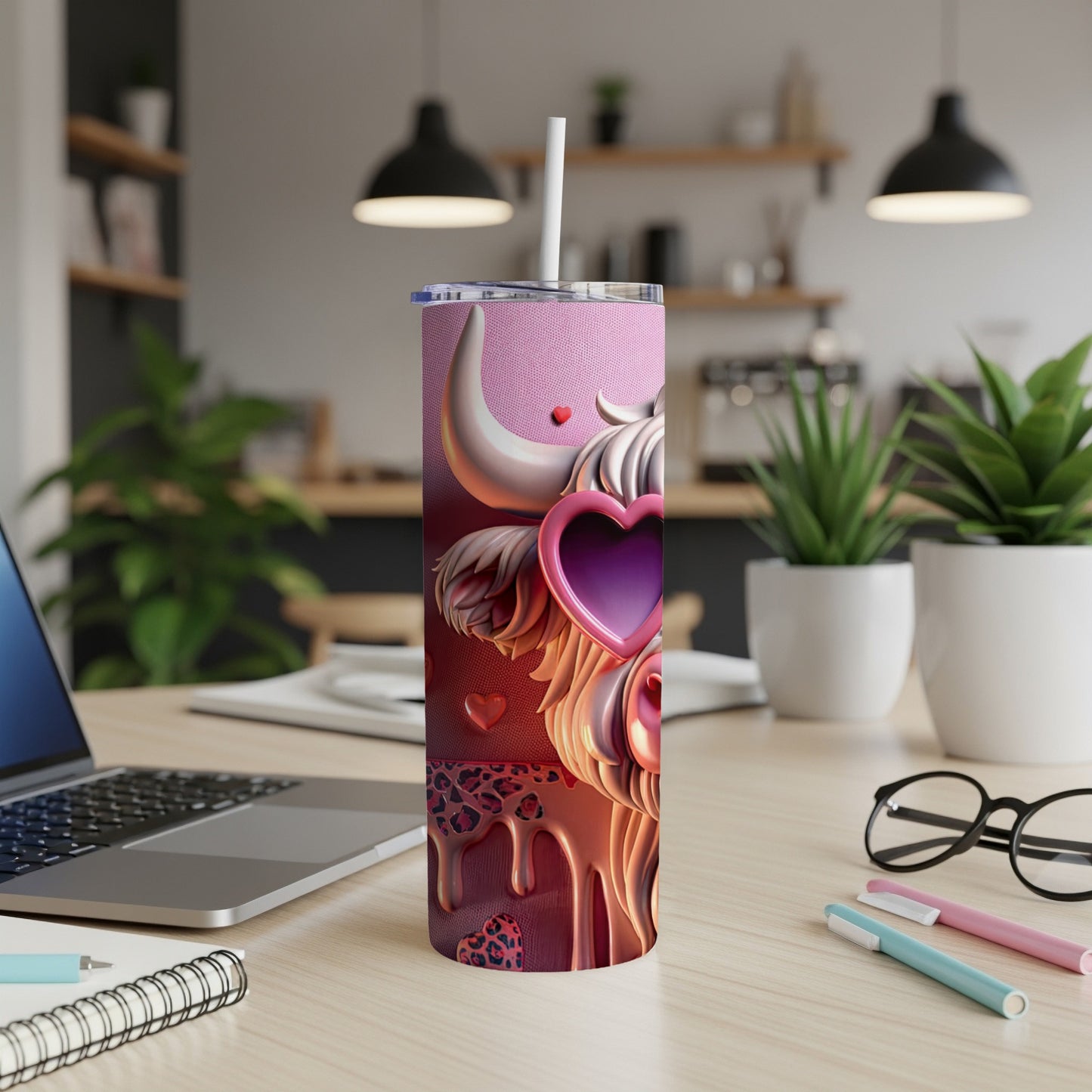 Pink tumbler with cow heart design, white straw, on a desk.