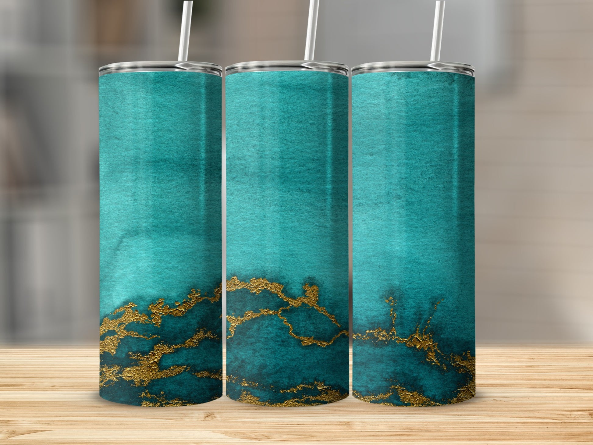 Three teal tumblers with gold marble design on a wooden surface.