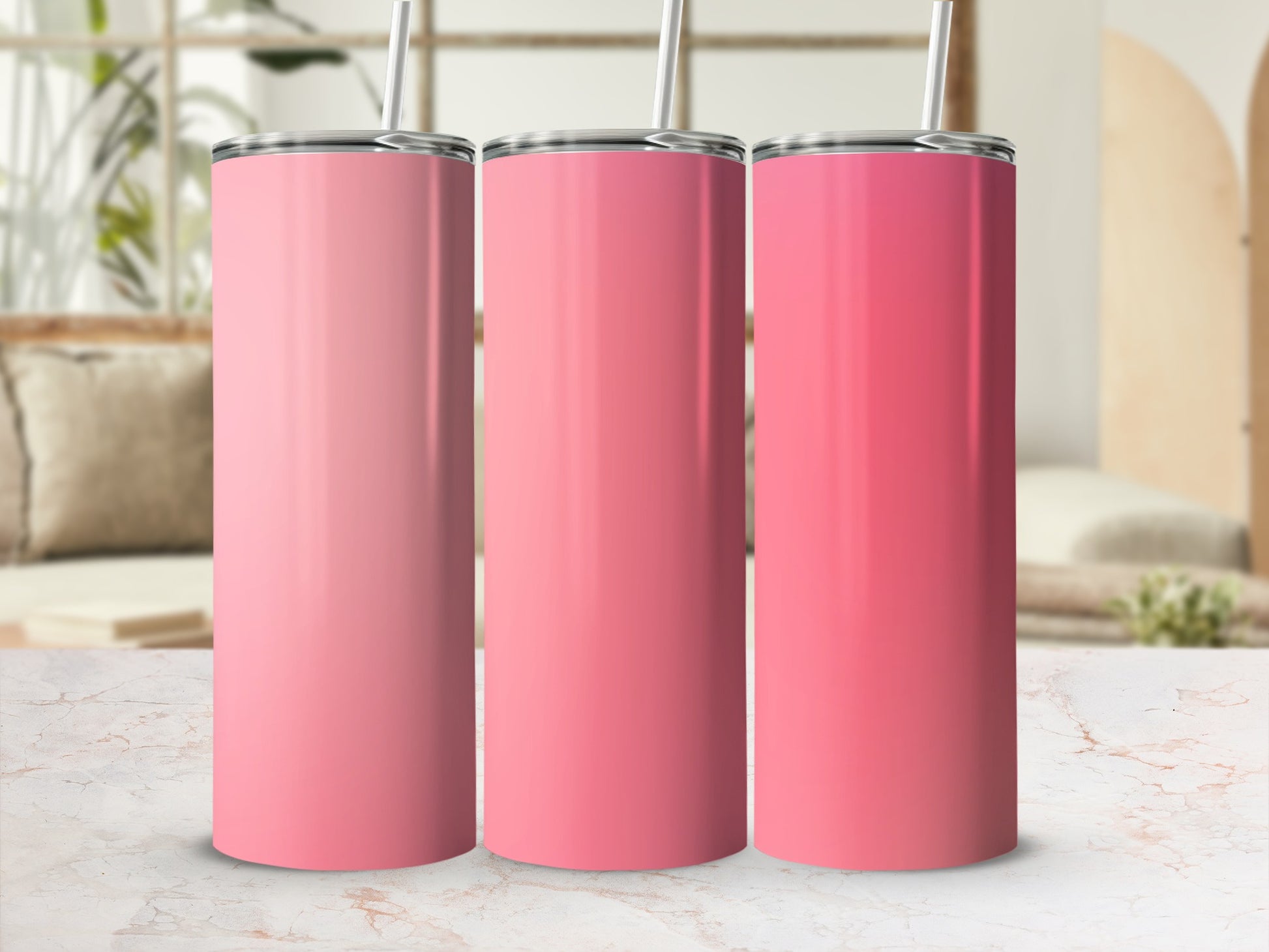 Three pink tumblers with straws on a marble surface.
