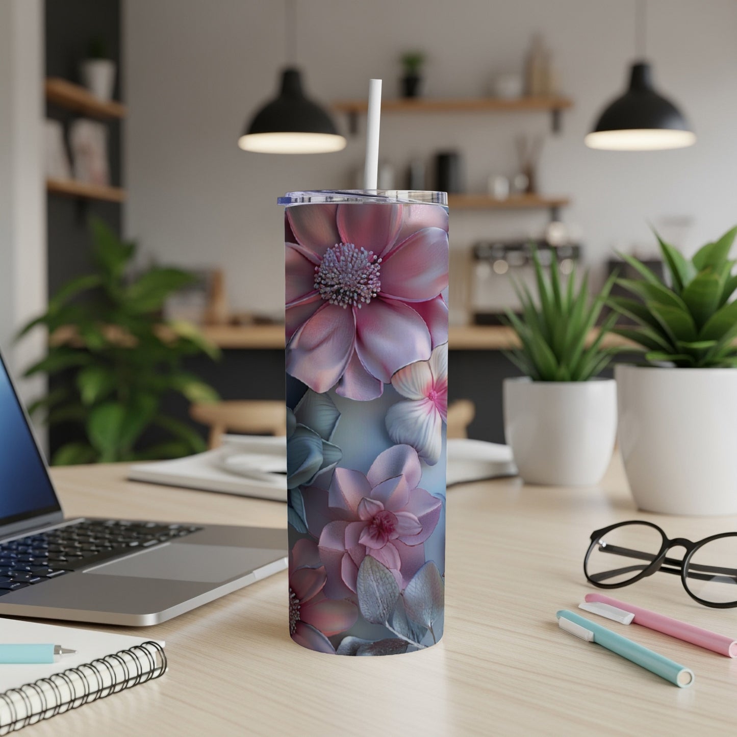 Pink and blue floral tumbler on a desk with a laptop and pens.
