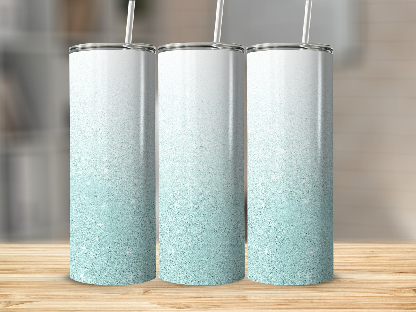 Three glitter-covered tumblers with a teal to white gradient and straws.